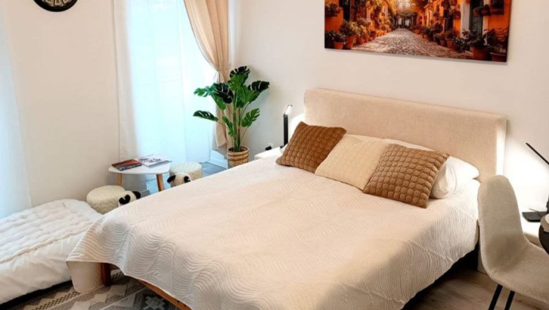 Cozy bedroom with double bed, plants and mural.