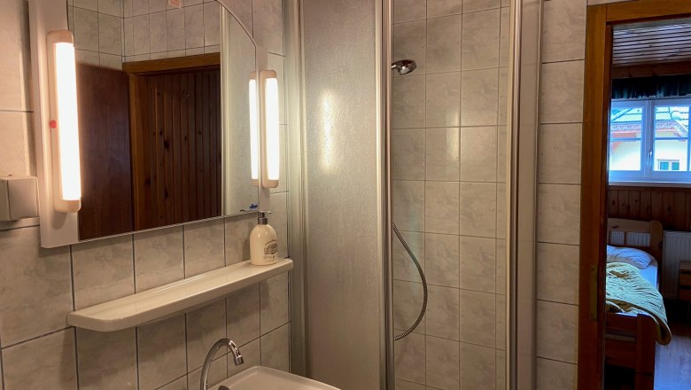 Bathroom with shower, washbasin and mirror with lighting.