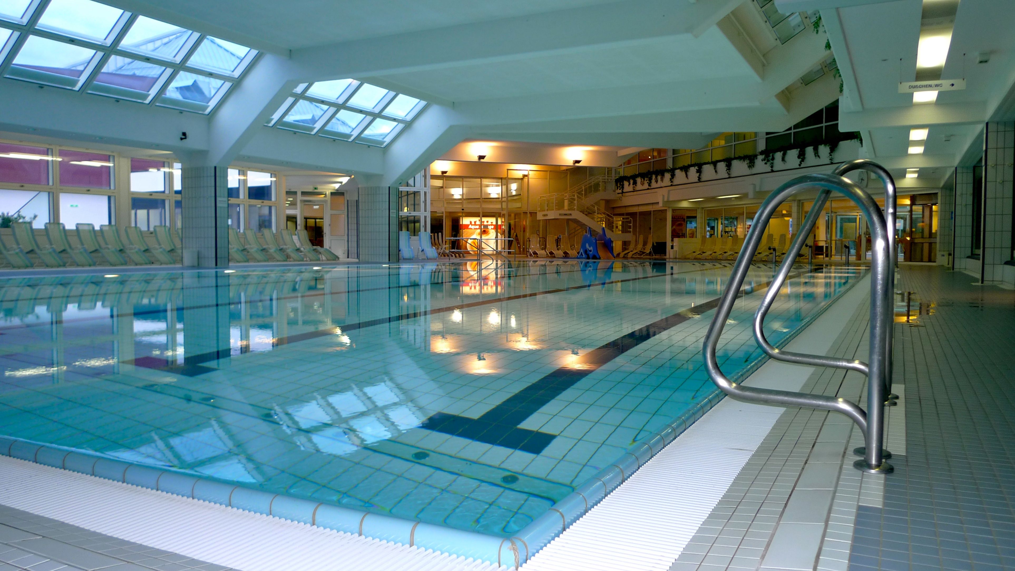 Interior view of a modern indoor pool with swimming pool and sun loungers.