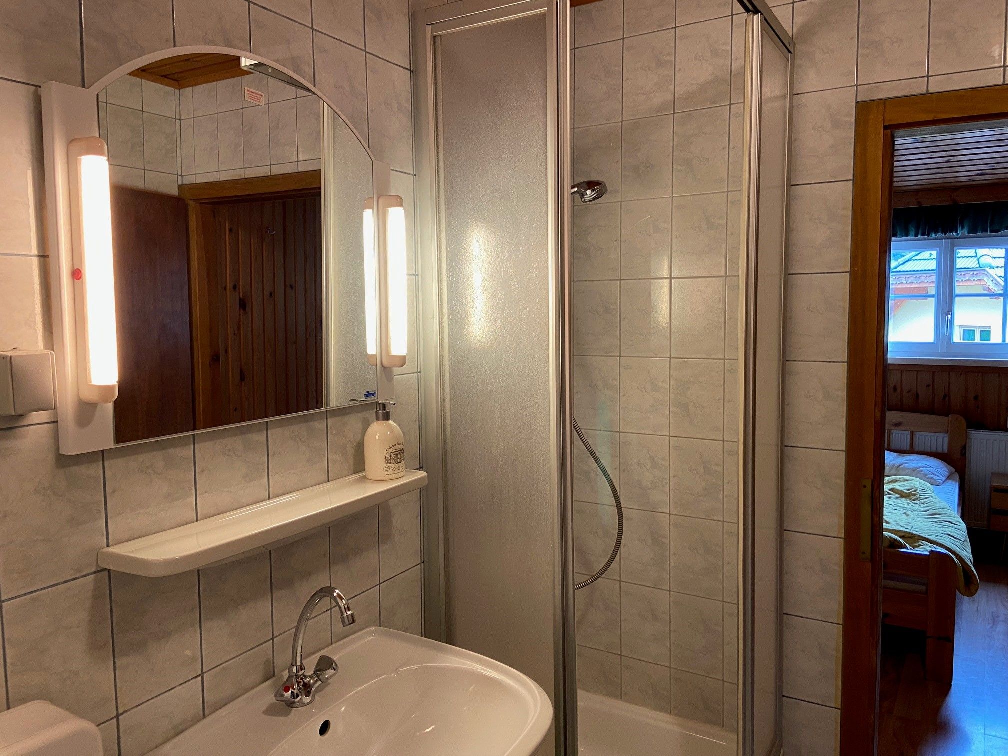 Bathroom with shower, washbasin and mirror with lighting.