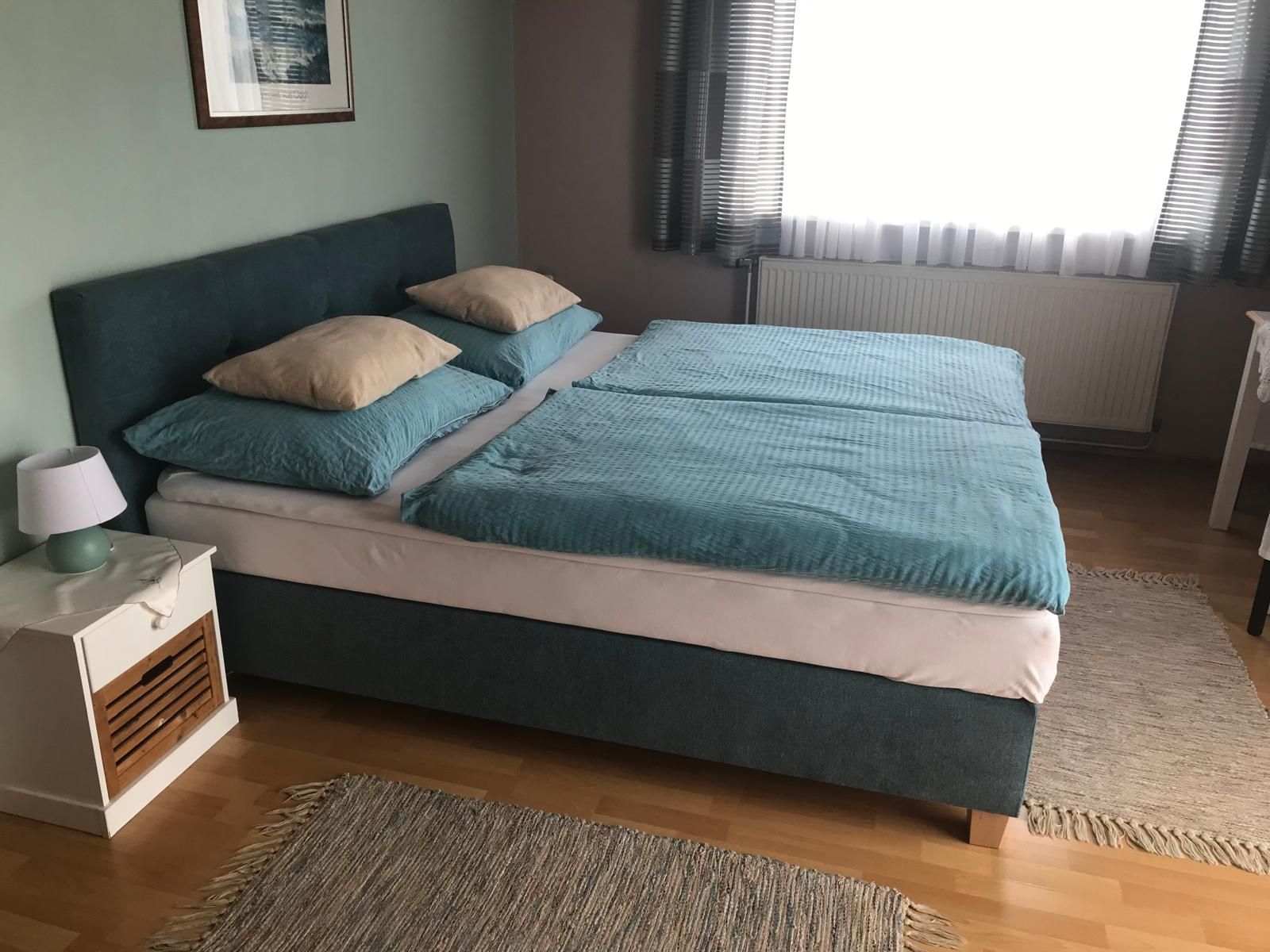 Bedroom with double bed, blue bed linen and bedside table with lamp.