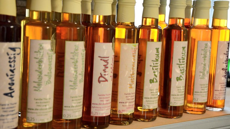 Various bottles of vinegar in a row on a shelf.