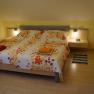 Comfortable bedroom with double bed, colorful floral bedding and bedside tables with lamps.