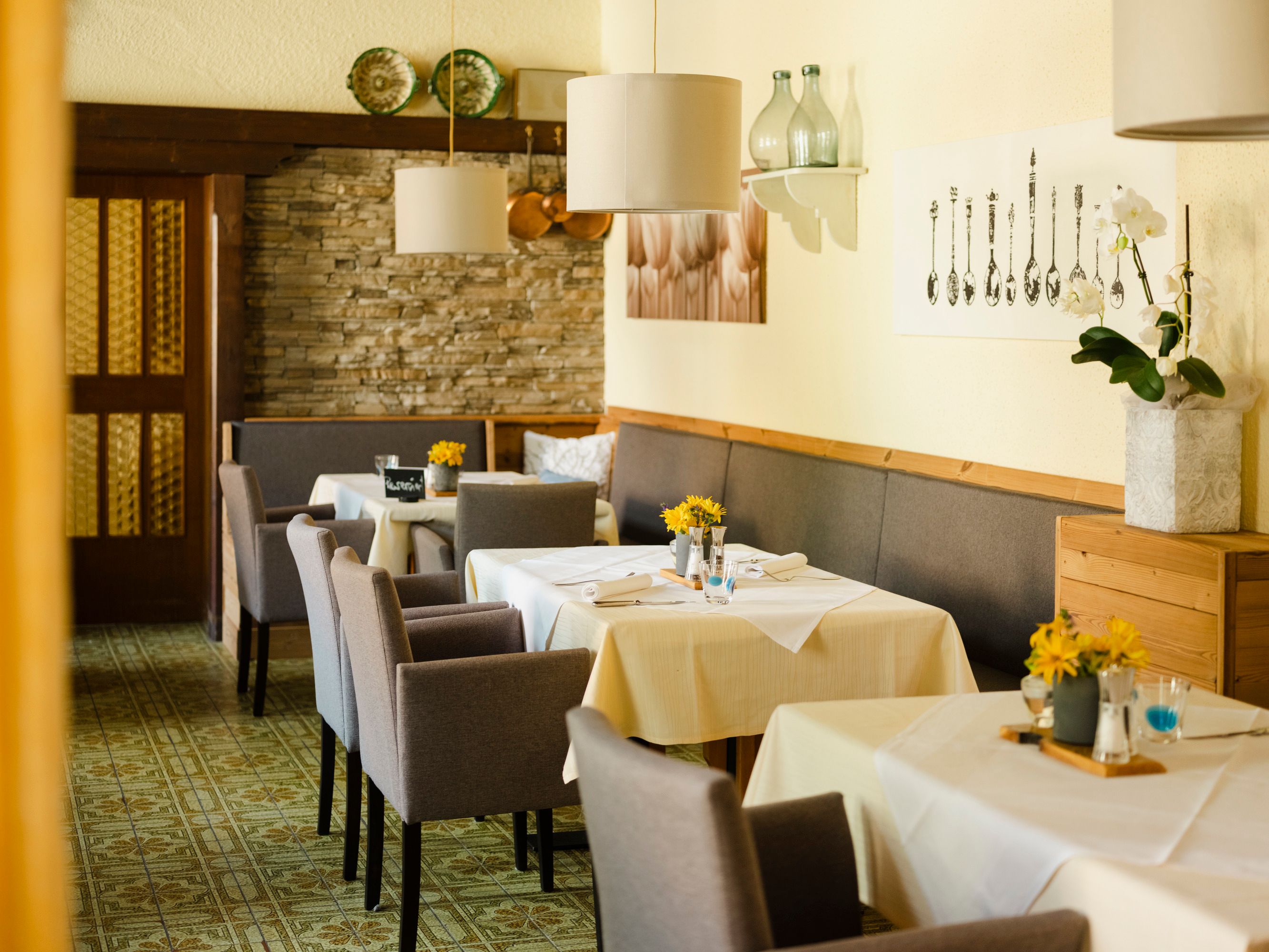 Inviting restaurant with laid tables, gray chairs and decorative elements on the walls.