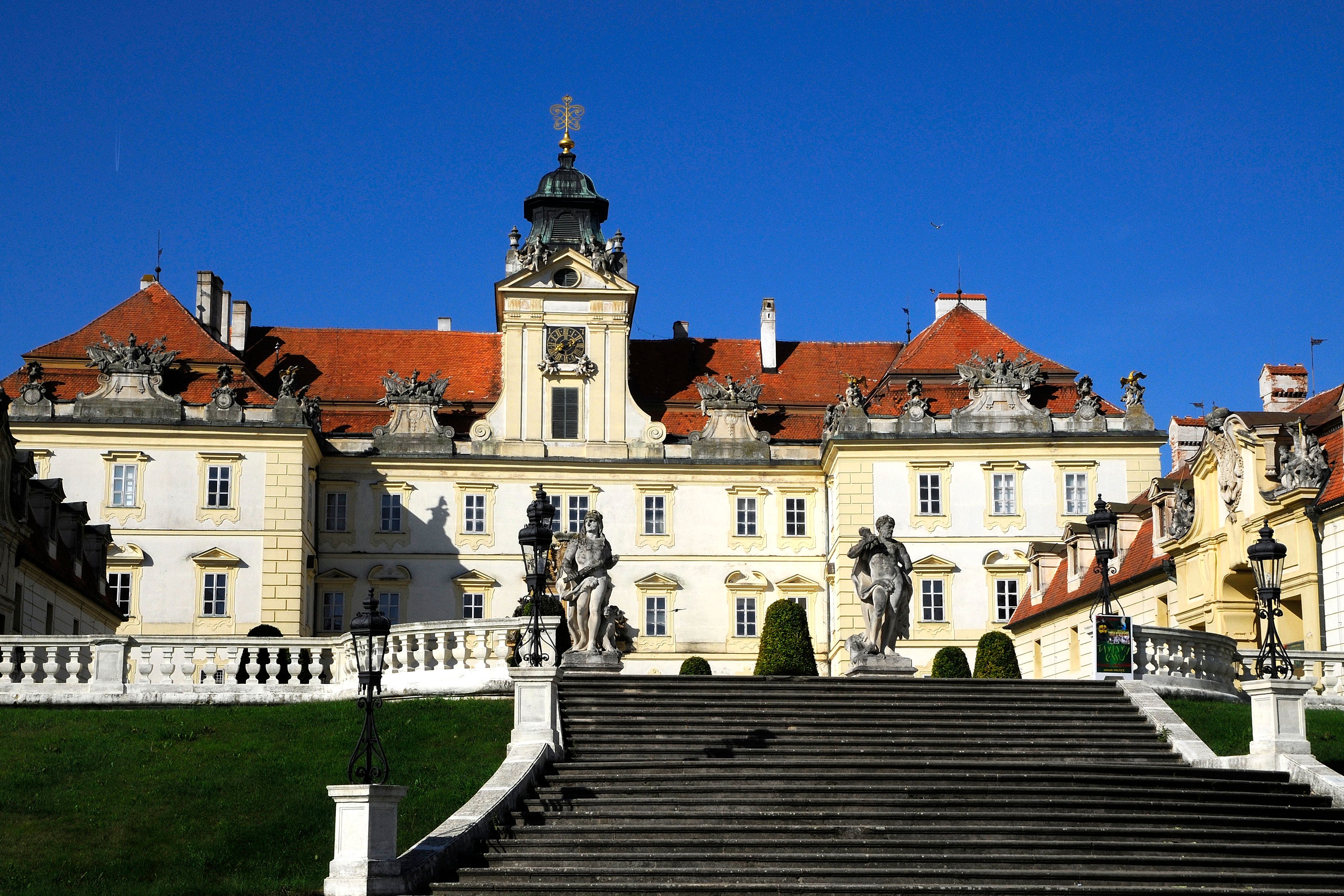 Front view of Valtice Castle with stairs and statues in the foreground.