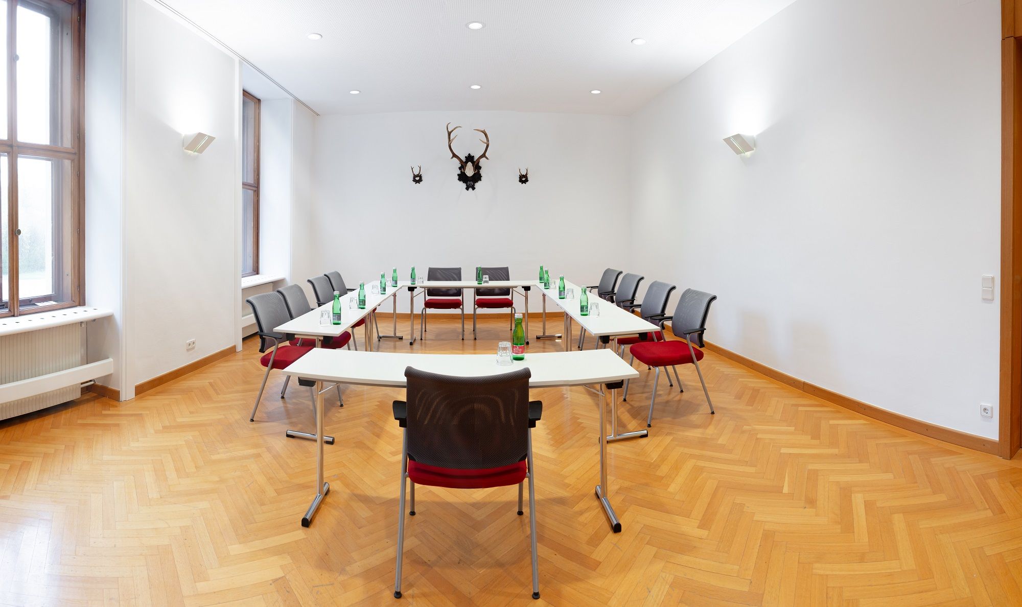 Seminar room with U-shaped table arrangement, chairs and water bottles.