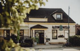 Traditional inn with signs and plants in the foreground.