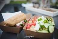 Quinoa salad with vegetables and bread served in paper bowls.