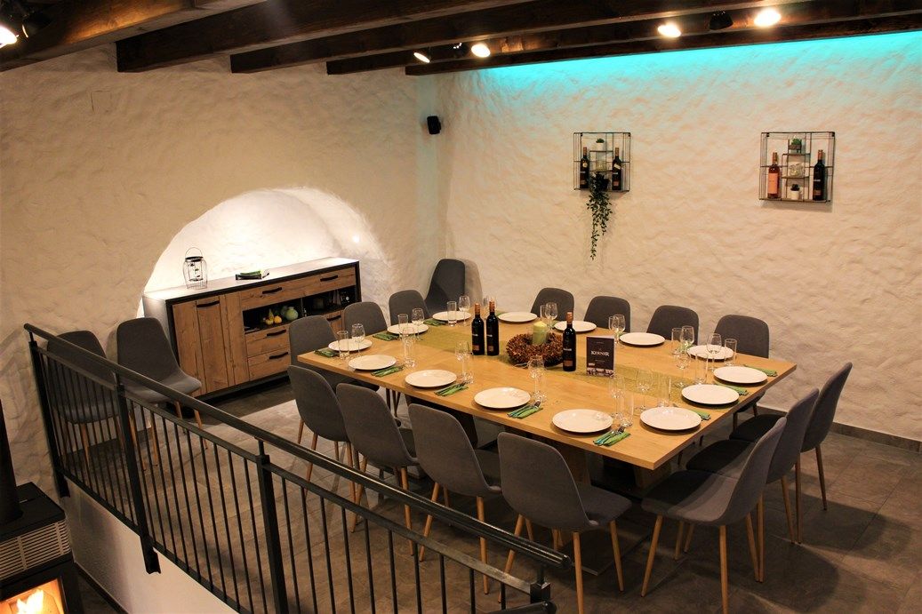 A stylishly laid table in a wine cellar with modern gray chairs and decorative lighting.