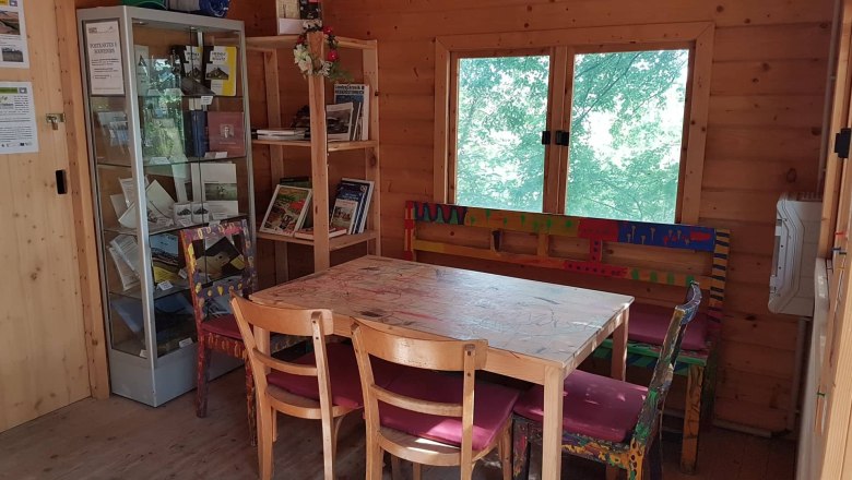 Interior view of a wooden room with table, chairs and bookshelves.