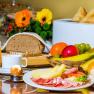 Breakfast buffet with bread, cold cuts, cheese, fruit, rolls, juice and egg.