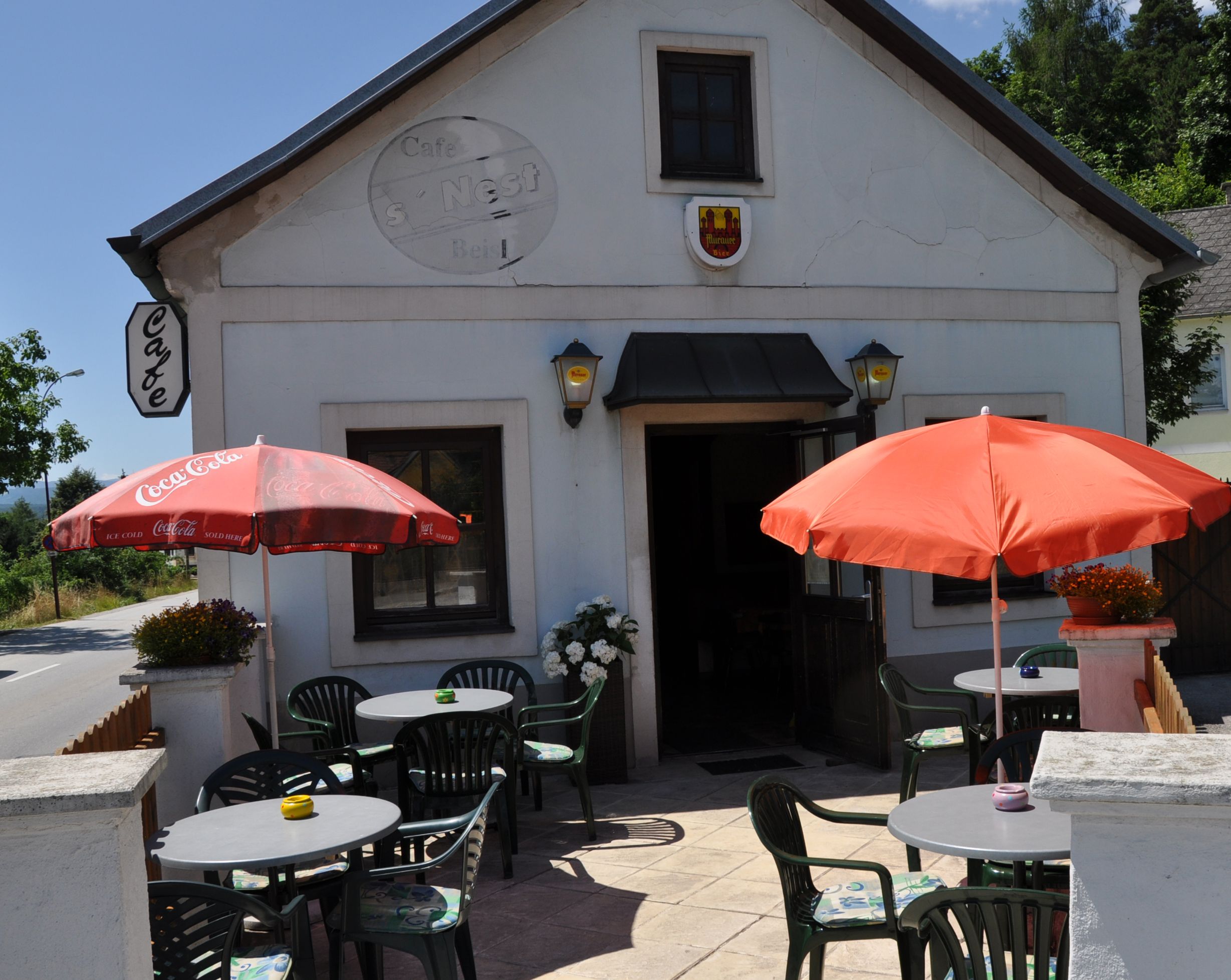 Exterior view of a café with terrace, tables and parasols.