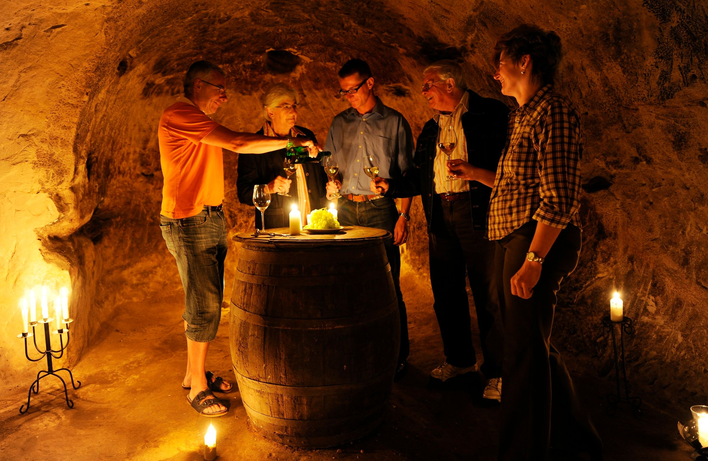 Group of people in a wine cellar tasting wine.