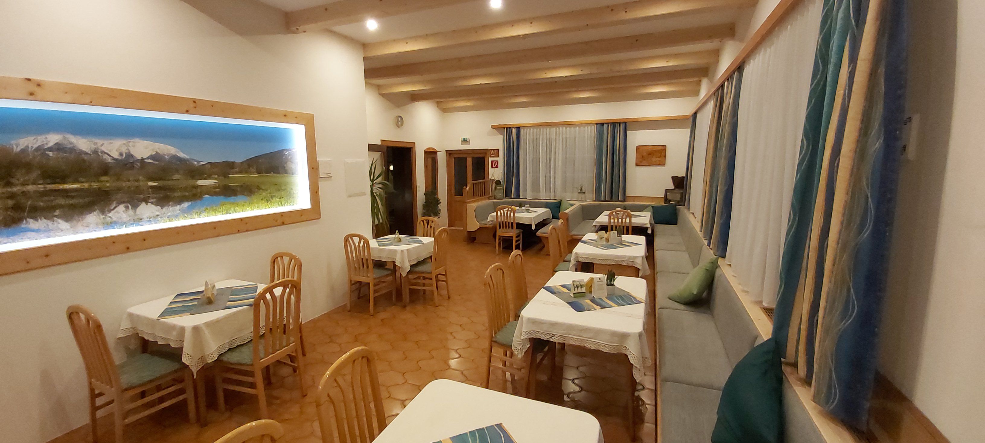 Cozy restaurant with wooden furniture and a mountain picture on the wall.