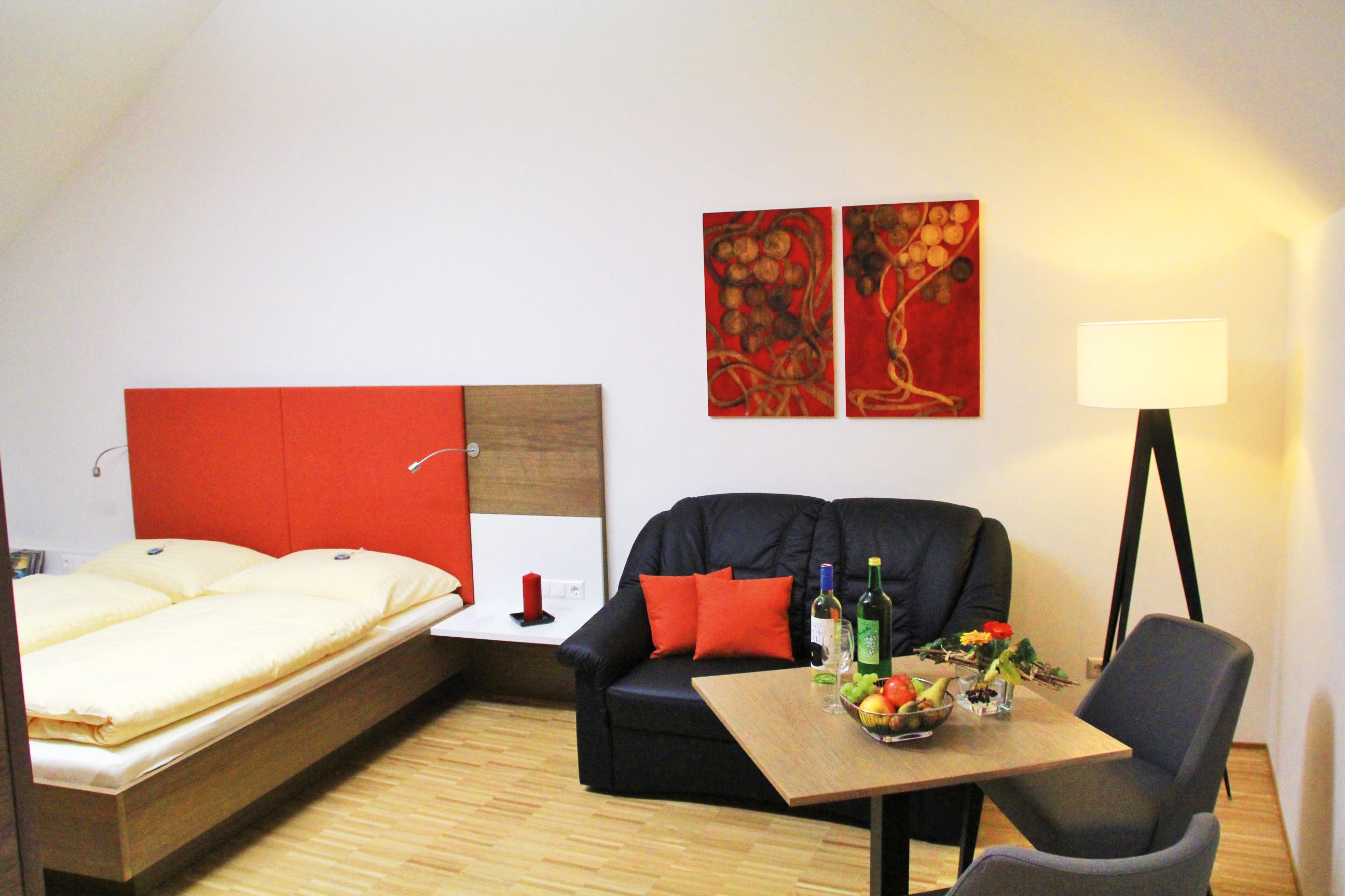 Cozy room with double bed, sofa, table and floor lamp.