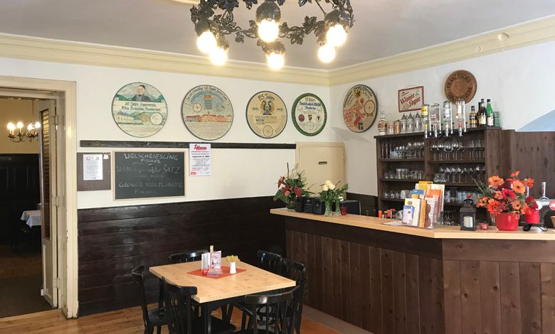 Interior view of a traditional brewery with wooden counter, tables and decorative beer mats on the wall.