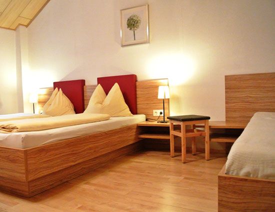 Cozy bedroom with wooden floor, double bed, bedside lamps and a stool.