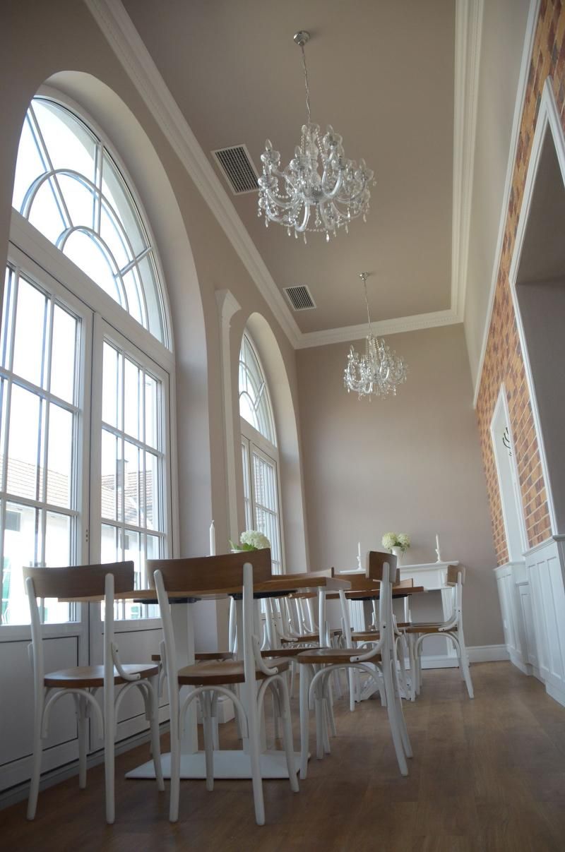 Elegant room with high windows, chandeliers and wooden furniture.