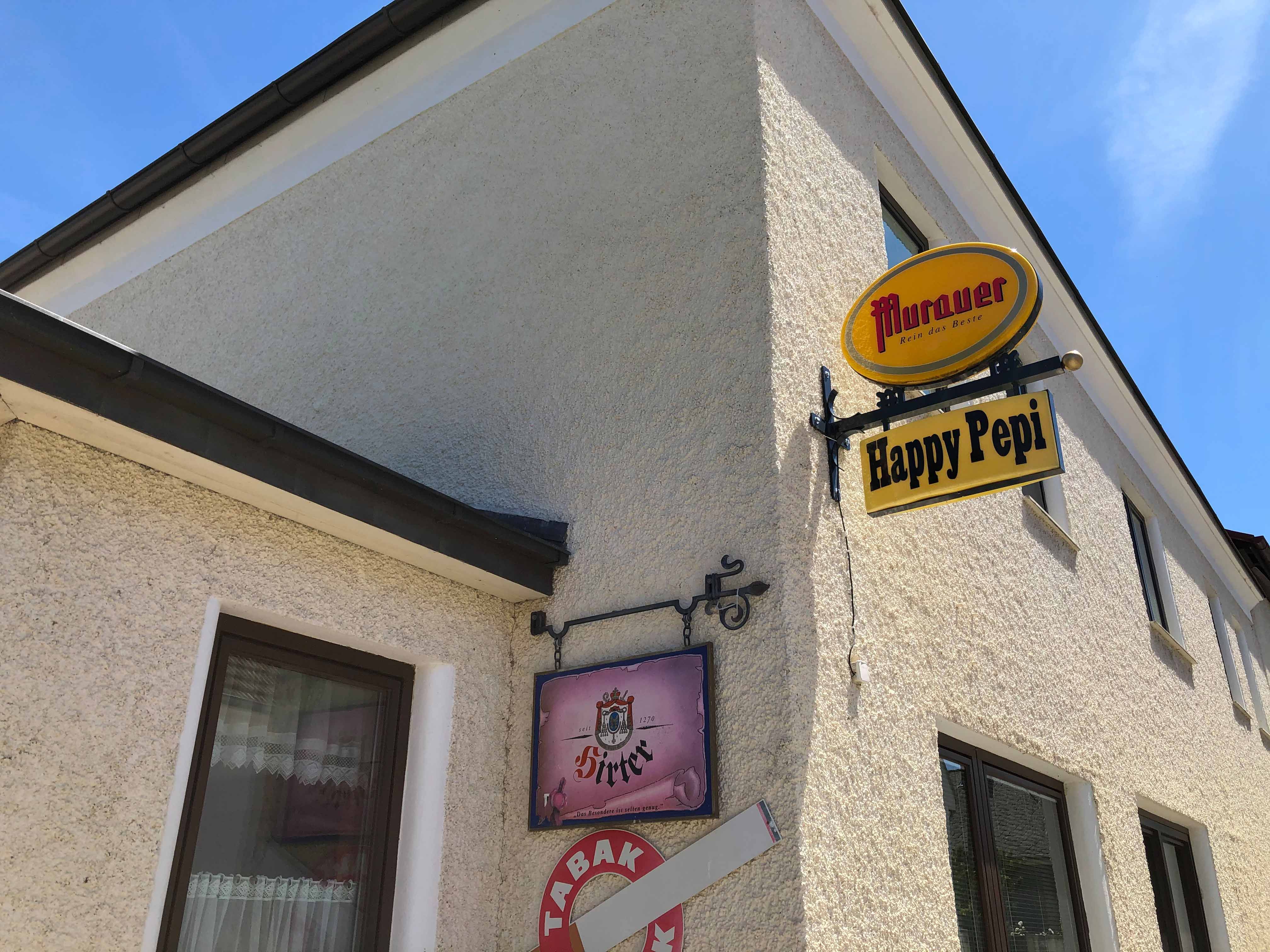 Exterior view of a building with signs for 'Murauer' and 'Happy Pepi'.