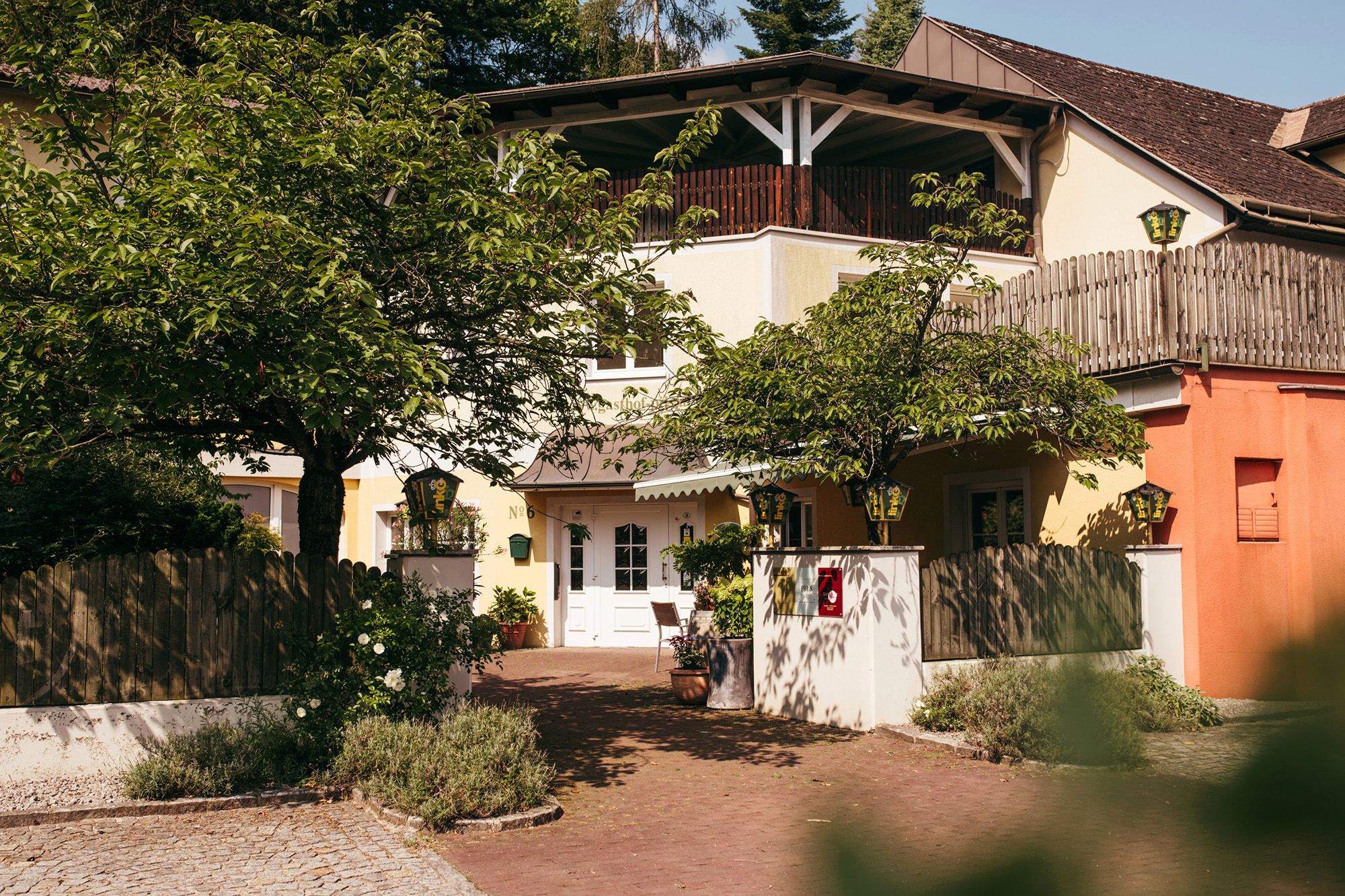 Entrance to an inn with trees and wooden fence.