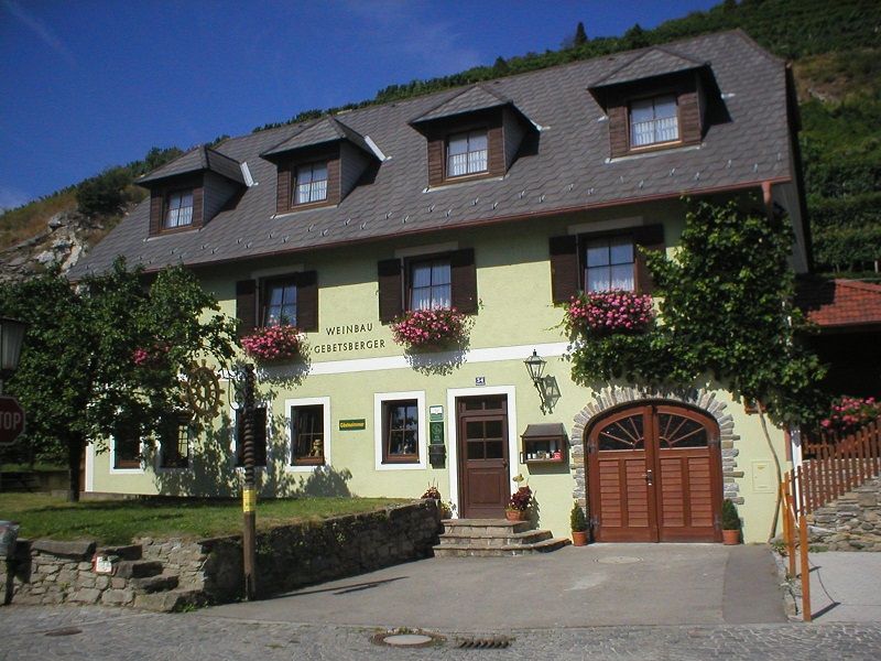 Exterior view of a winery with yellow facade and flowers.