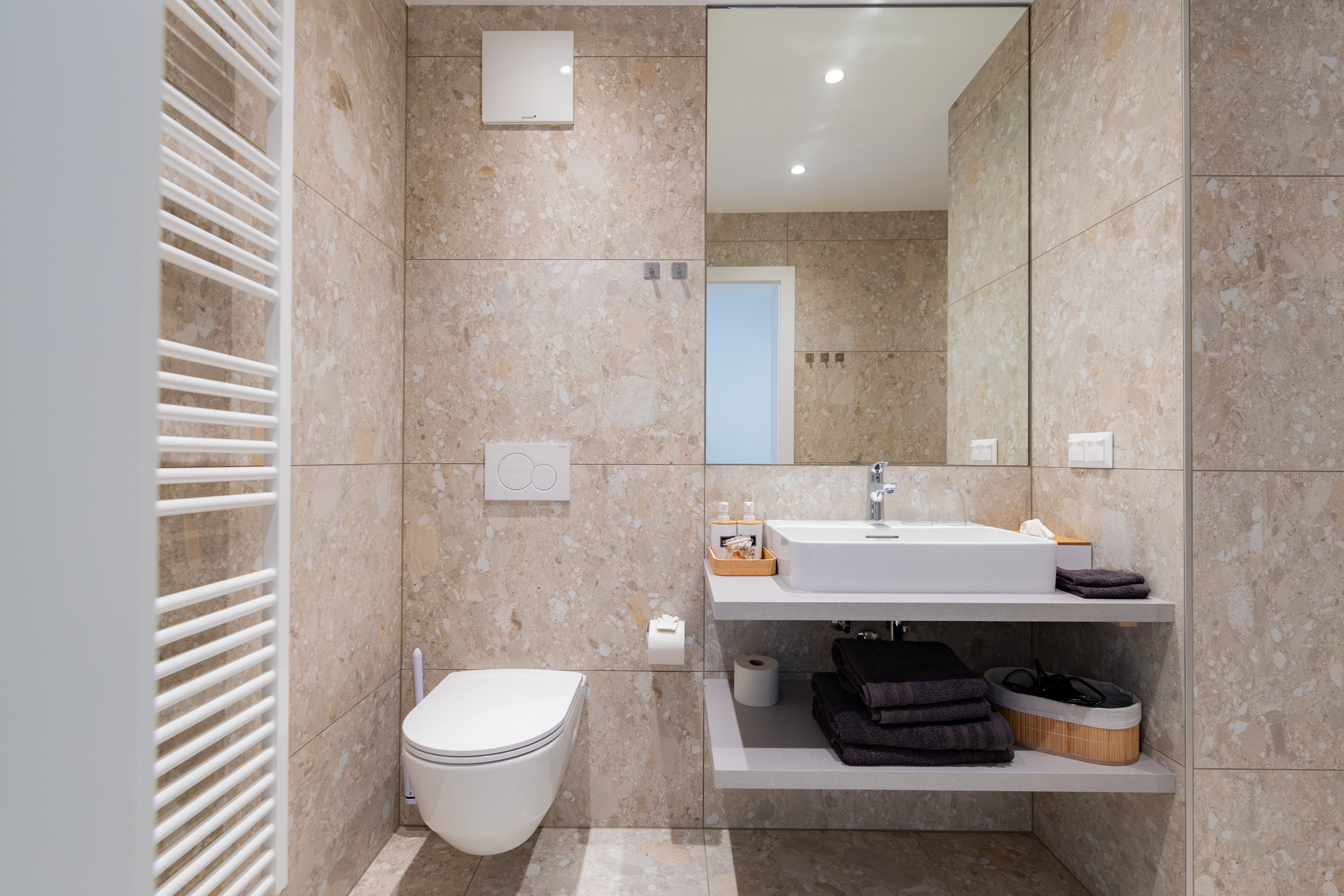Modern bathroom with washbasin, mirror, toilet and towel rail.