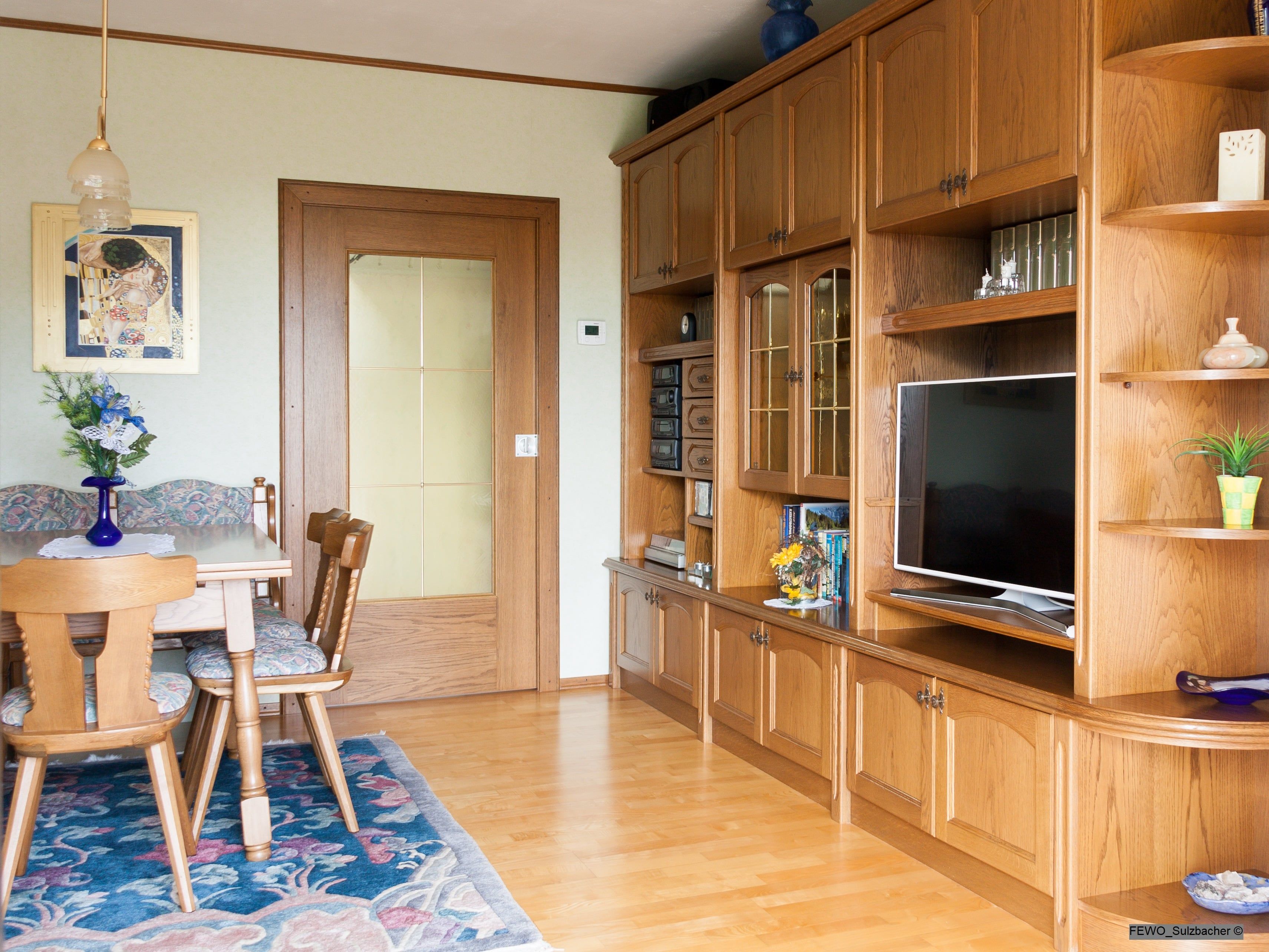 A traditional living room with wooden furniture, a dining table, chairs and a TV.