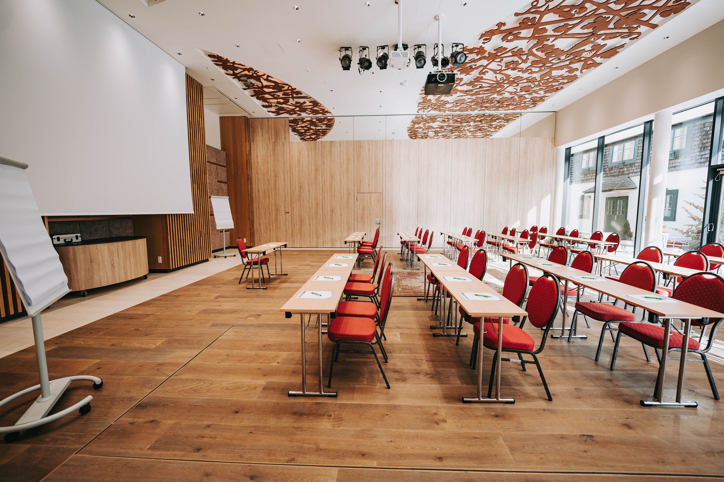 Interior view of a modern conference room with red chairs and wooden floor.