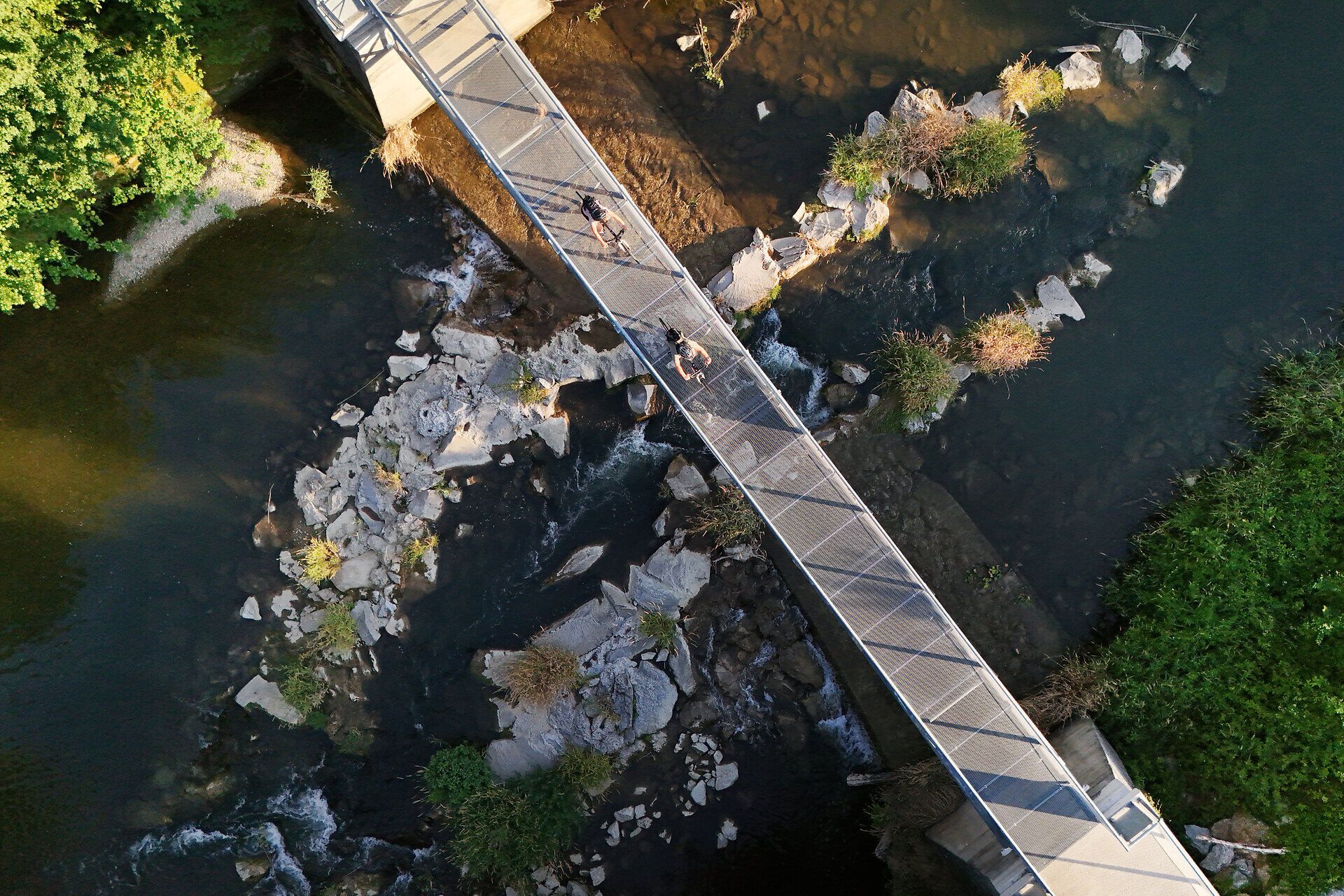 Cyclists cross a bridge in the Melk Alpine Foothills.