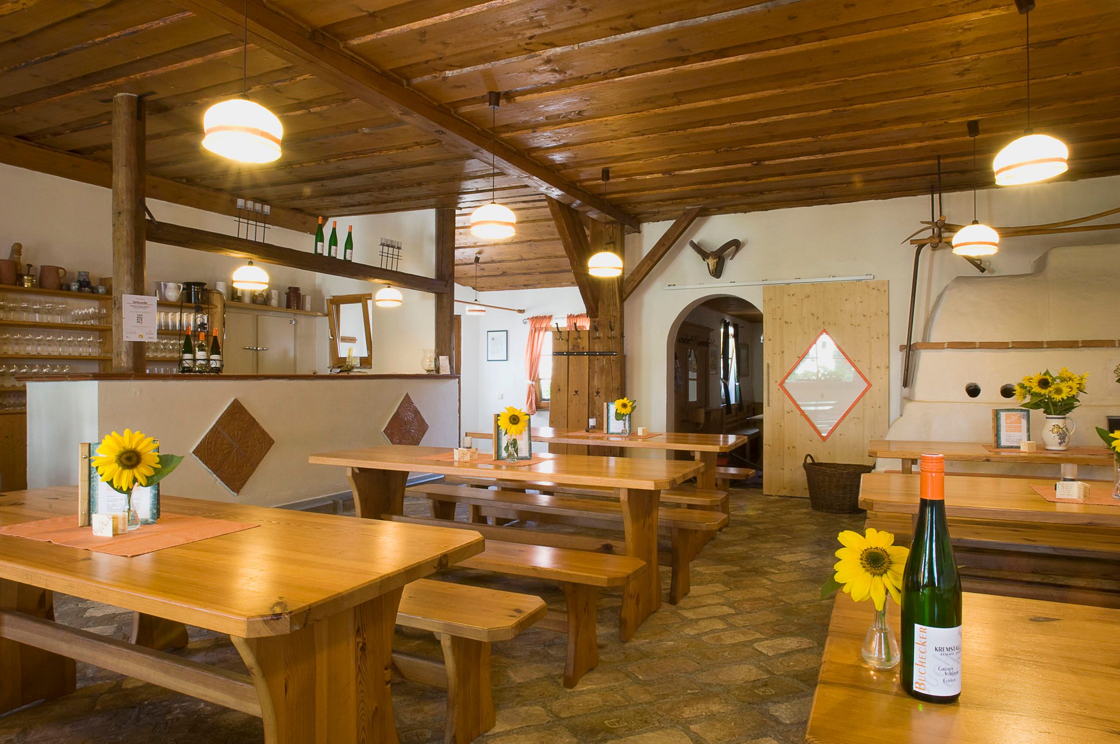 Interior view of a traditional wine tavern with wooden tables, sunflowers and bottles of wine.