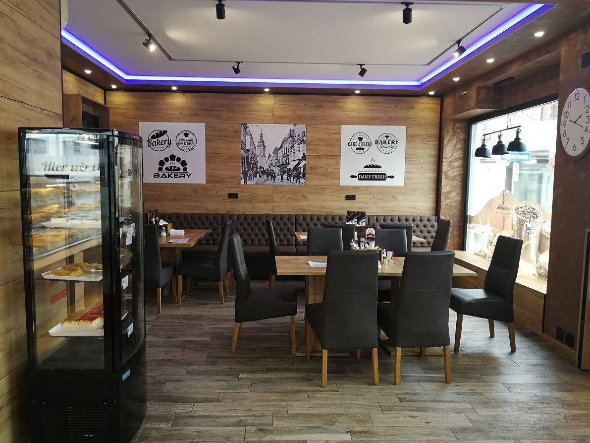Interior view of a modern bakery with wooden walls, tables and chairs.