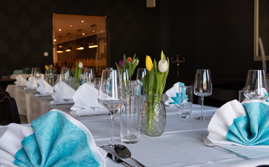 Elegant table with white tablecloths, turquoise napkins and tulips in vases.
