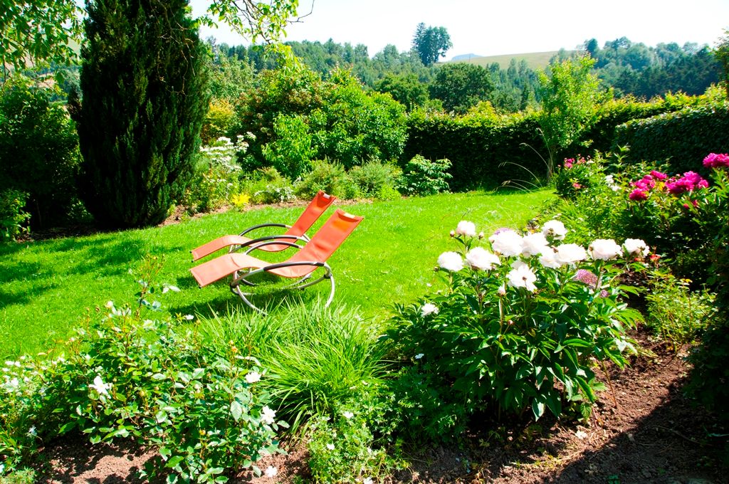 Garden with two red deckchairs and blooming flowers.