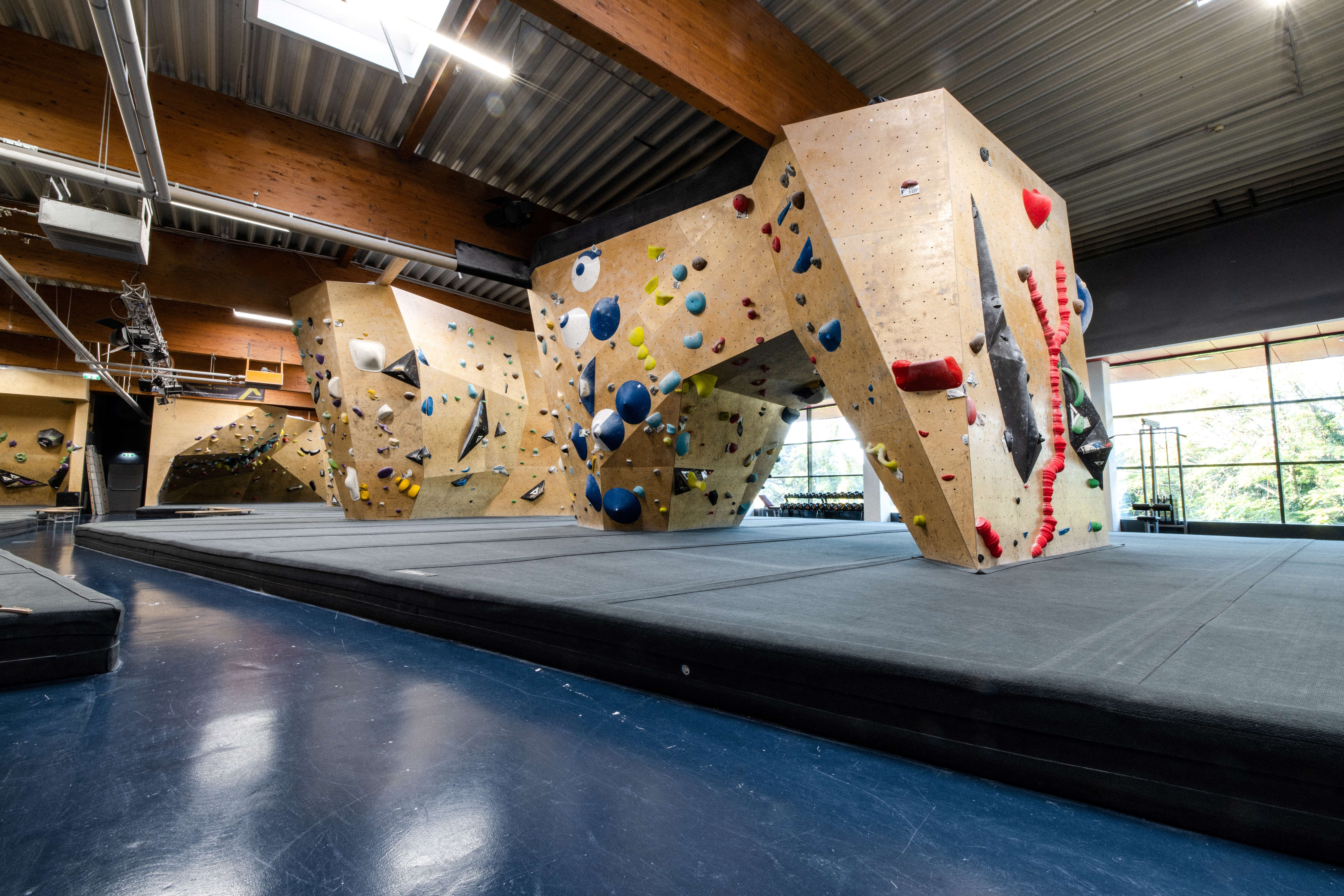 Interior view of a climbing hall with various climbing walls and colorful holds.