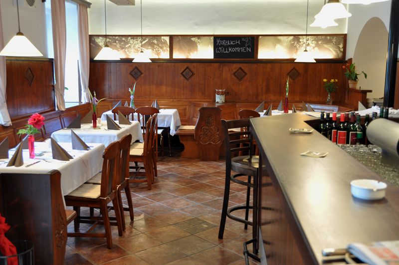 Interior view of a cozy restaurant with wooden furniture and laid tables.