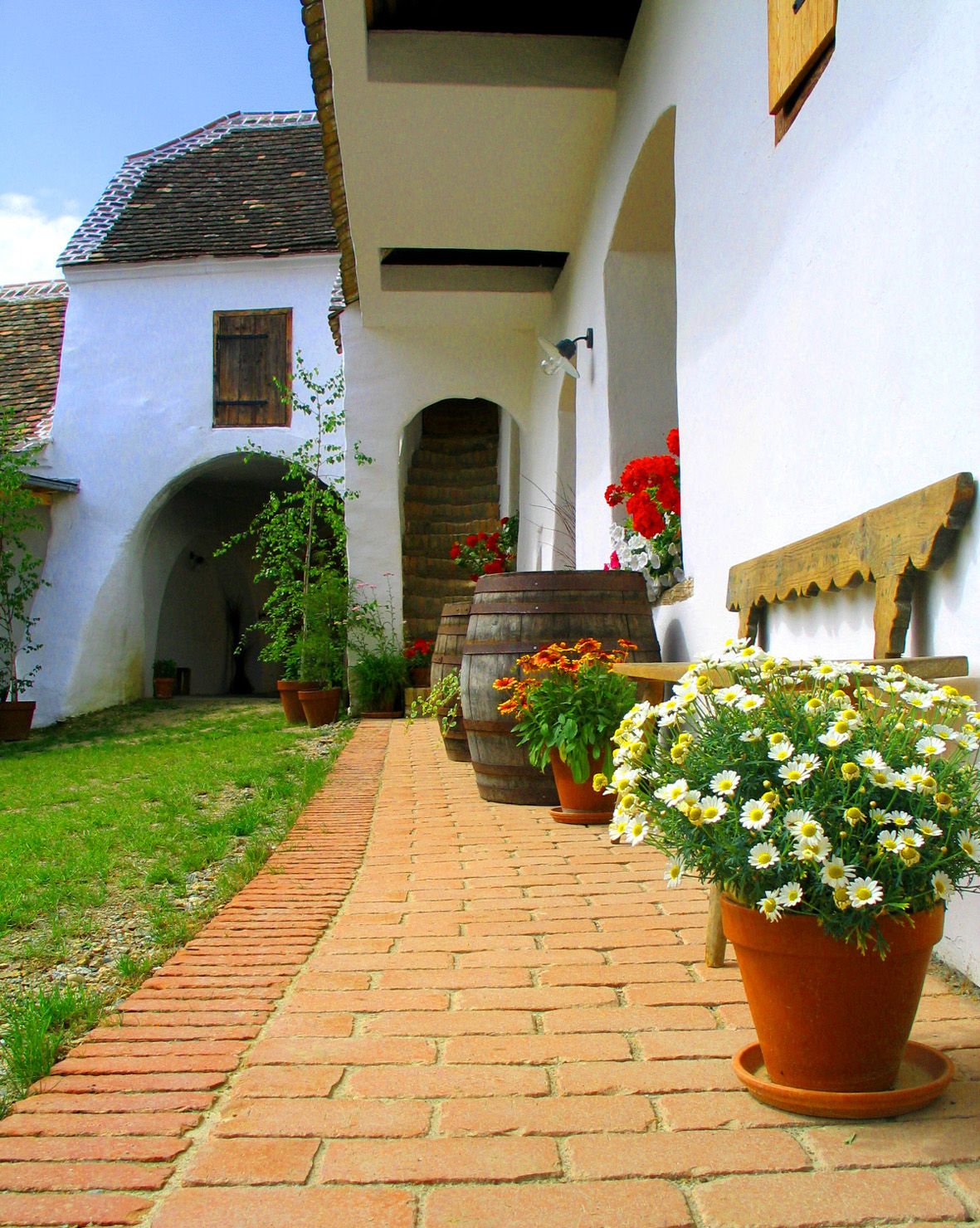 Traditional courtyard with flowers and wooden barrels.