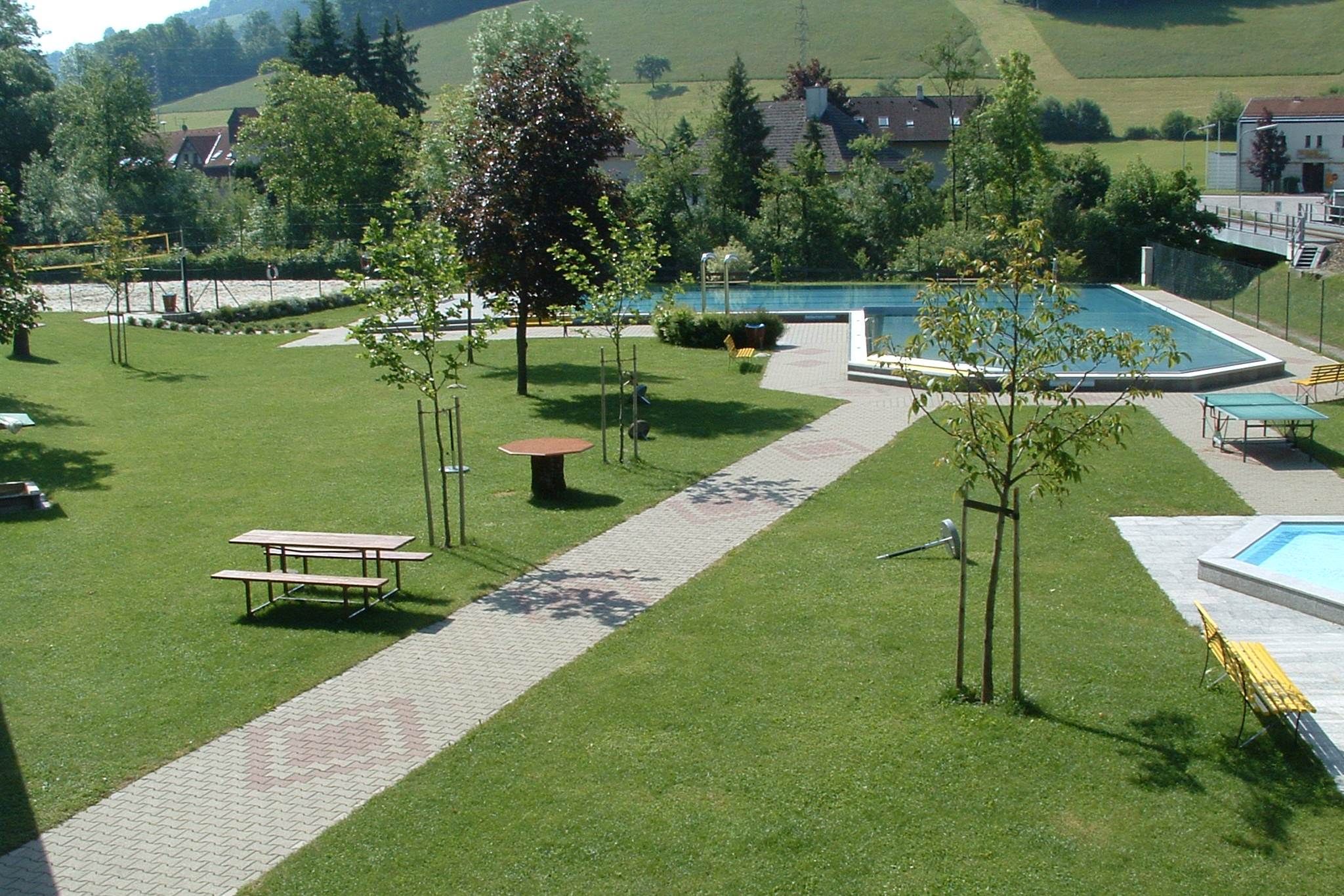 Green park with swimming pool and benches.
