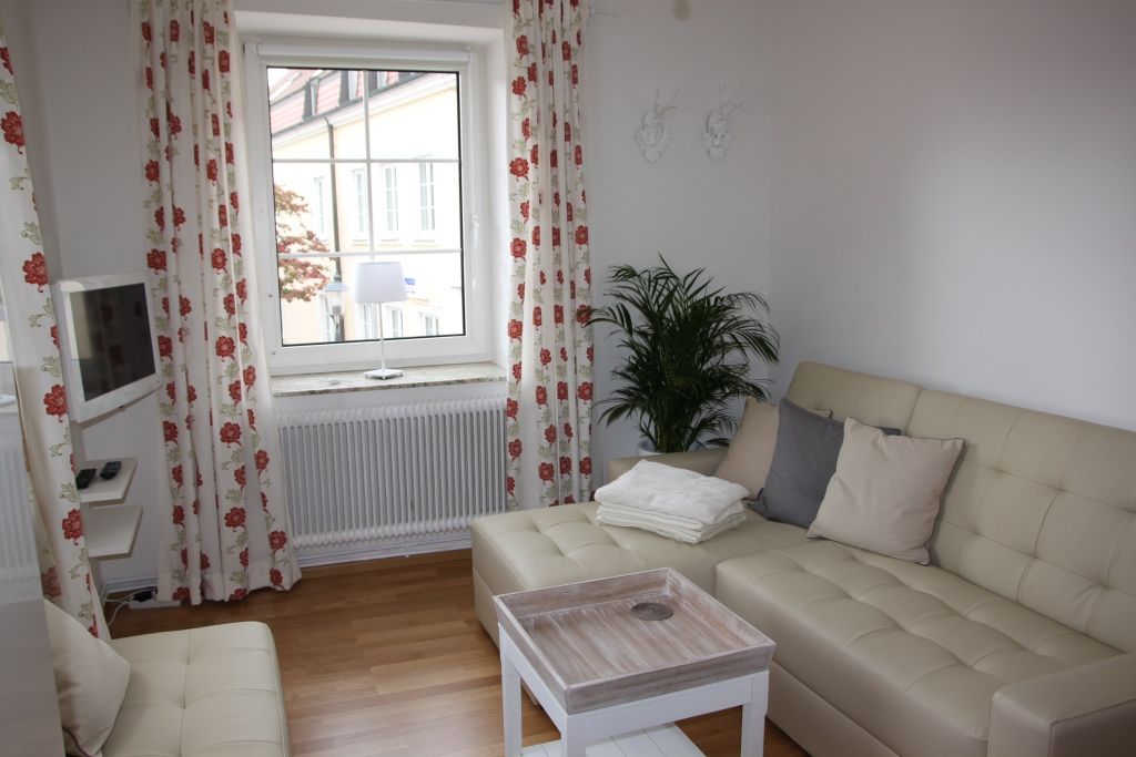 Bright living room with beige sofa, cushions, coffee table and window with curtains.