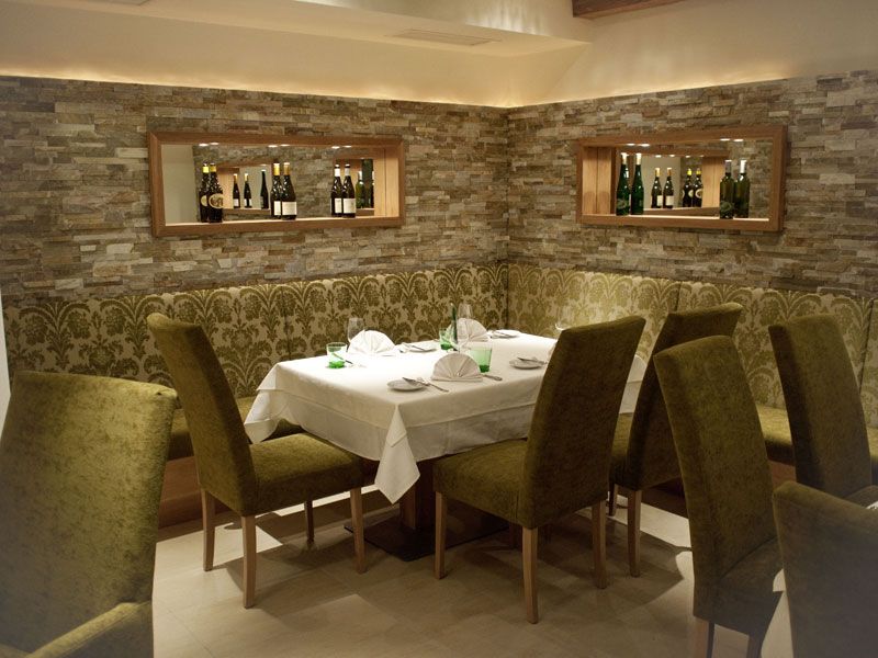 Elegant restaurant with laid table and green chairs.