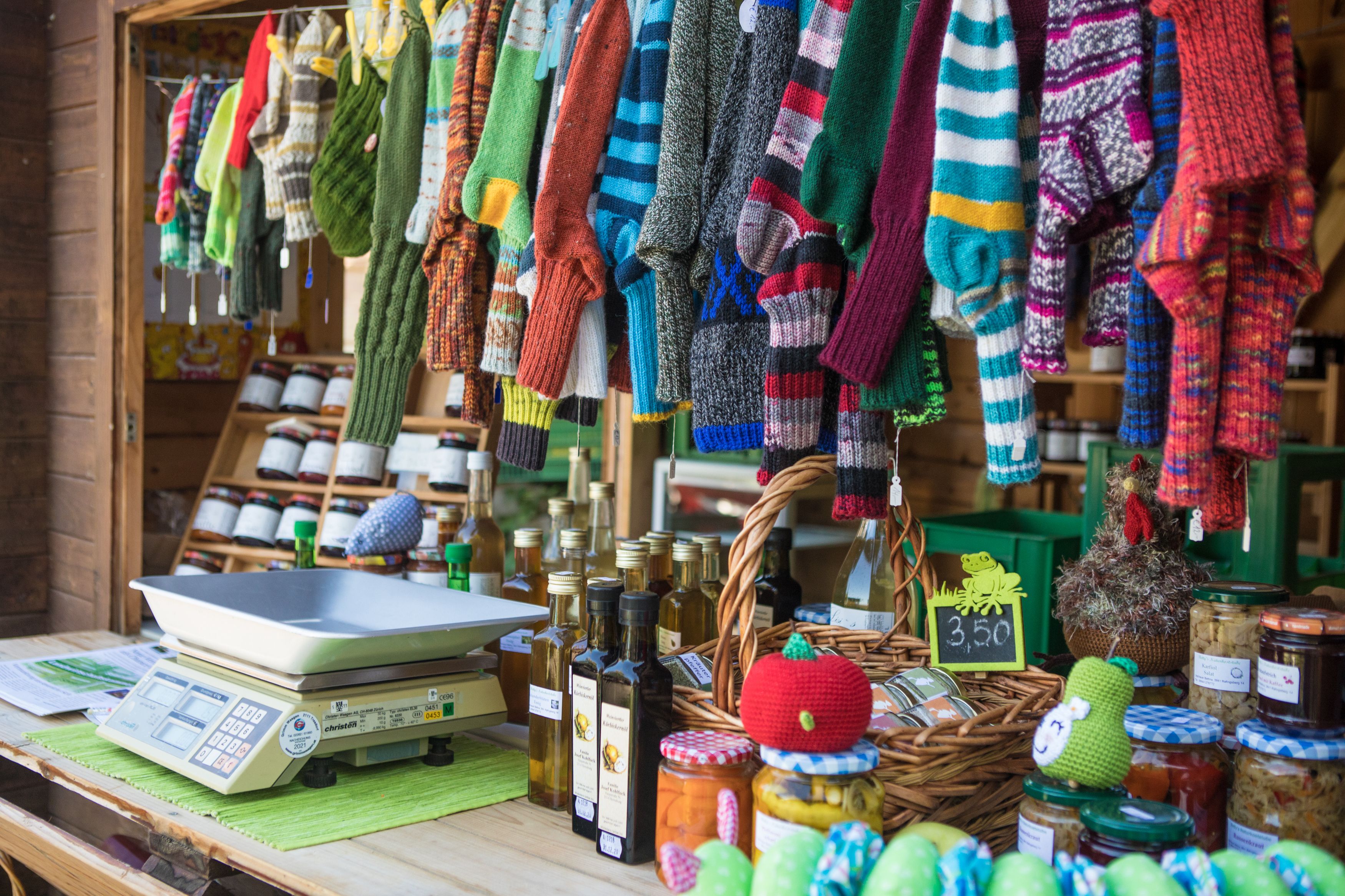 Market stall with knitted socks, oil bottles and preserving jars.
