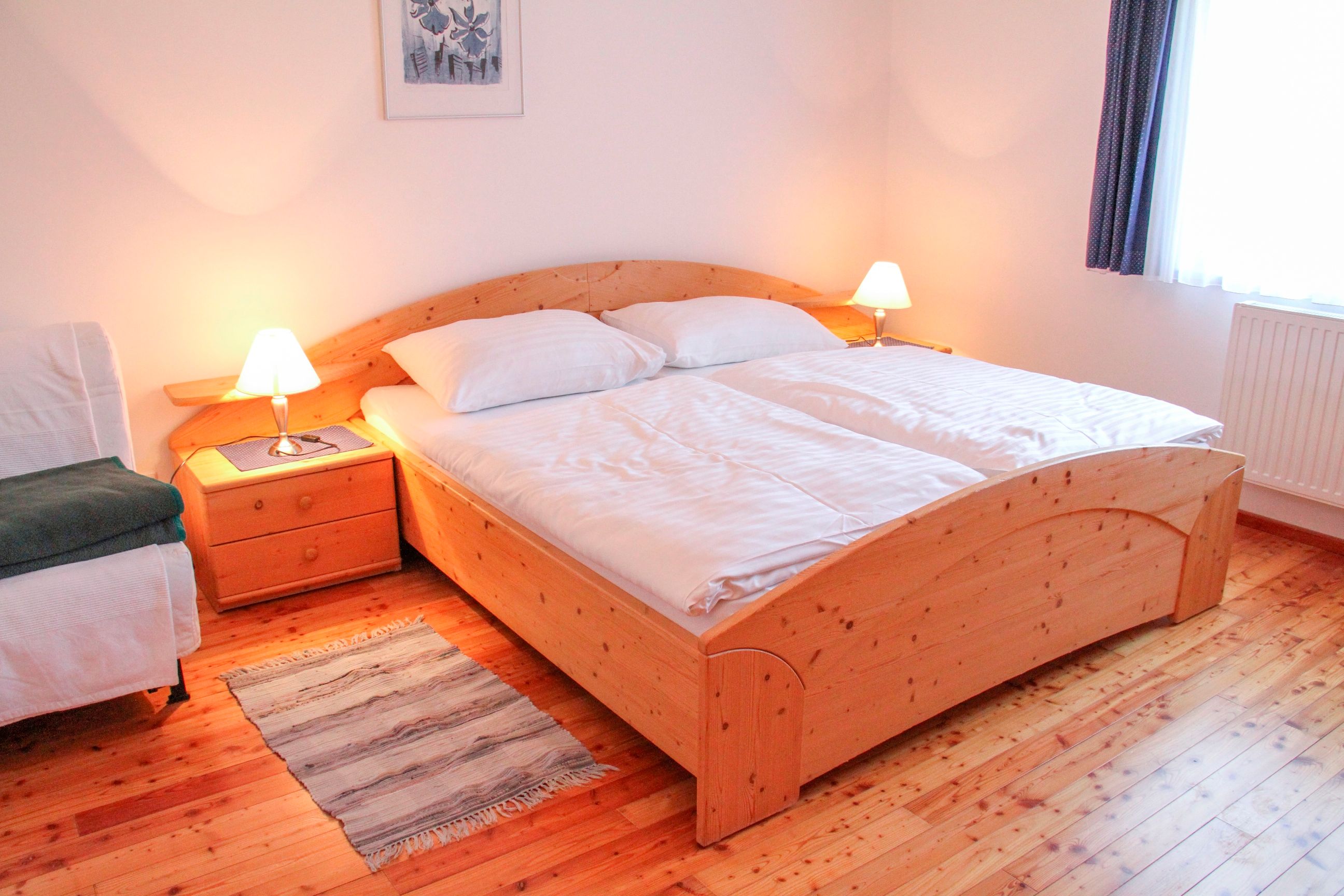 Cozy bedroom with double bed, wooden floor and bedside tables with lamps.
