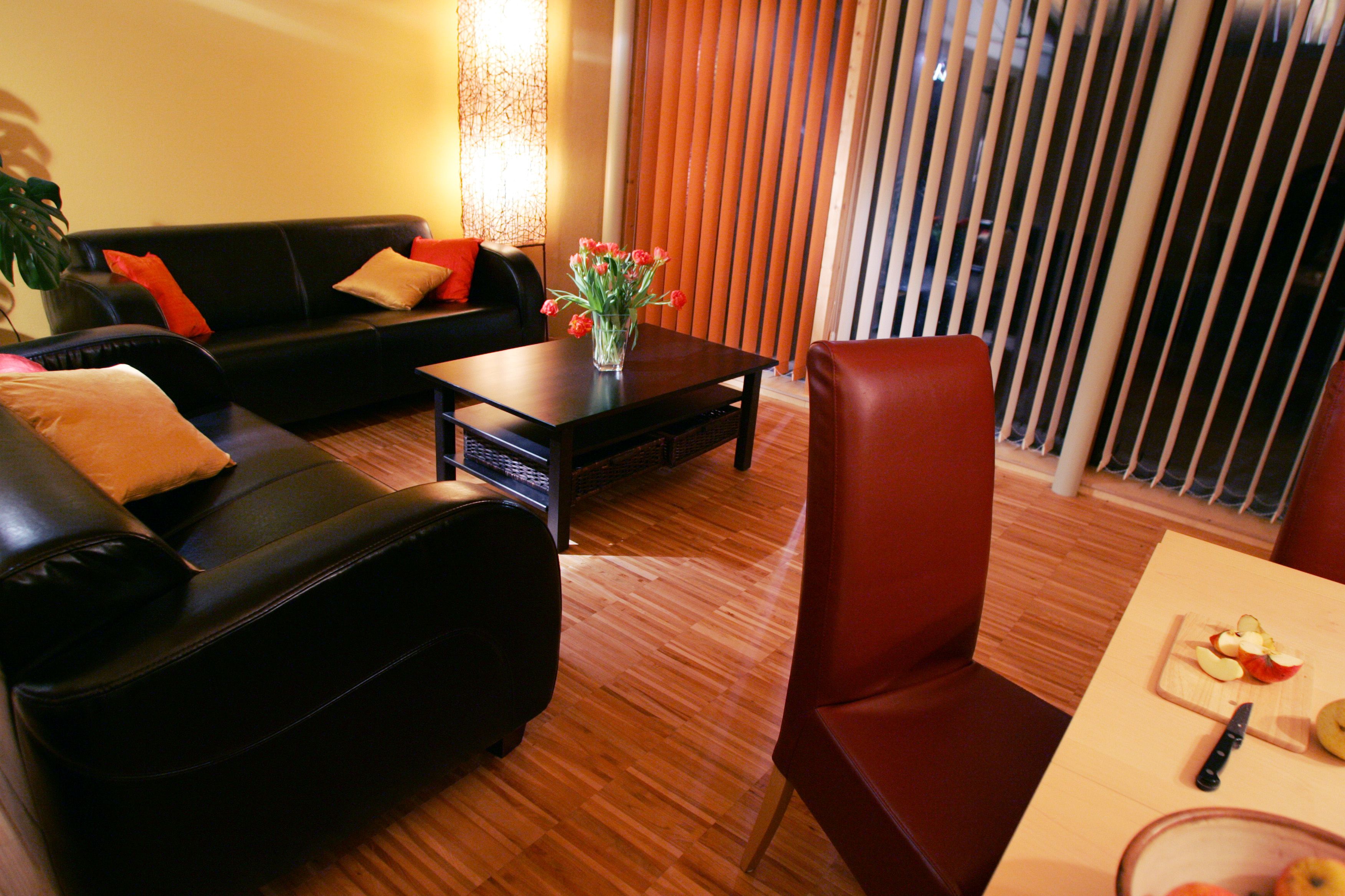Cozy living room with leather sofas, coffee table, bouquet of flowers and dining table with fruit.