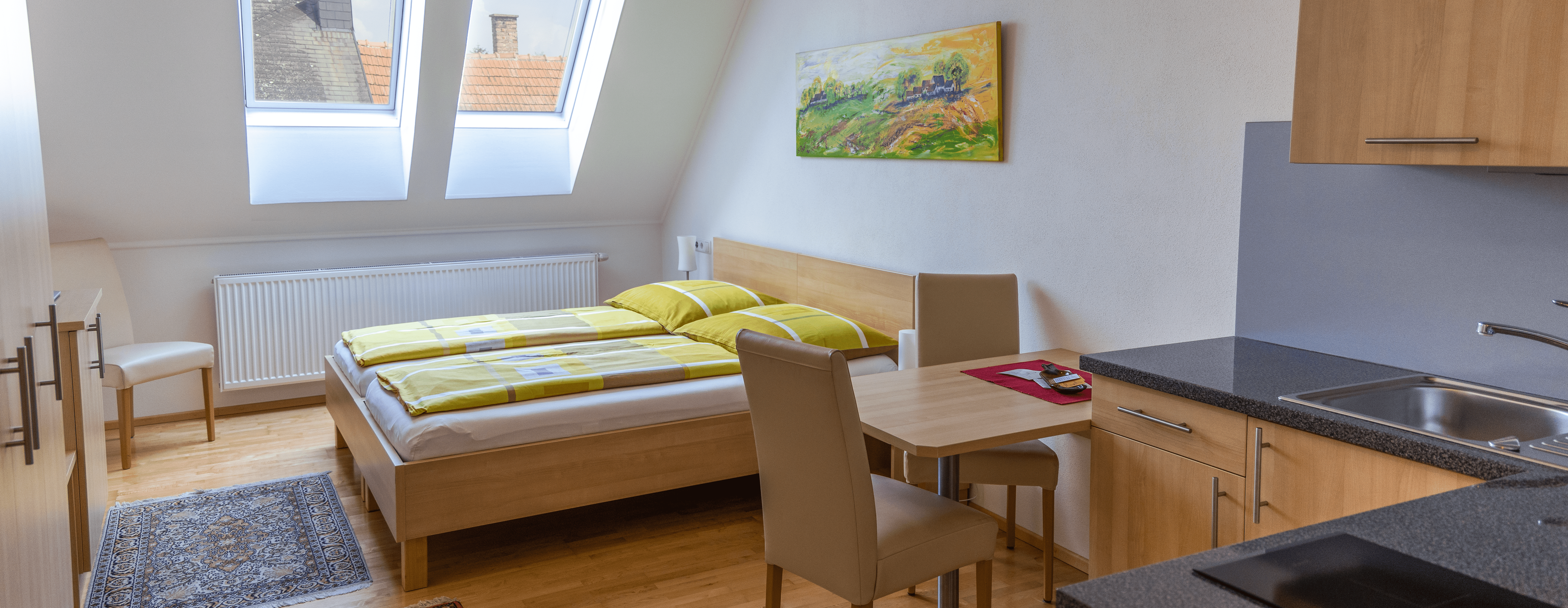 Double room with kitchenette, bed, table and chairs.