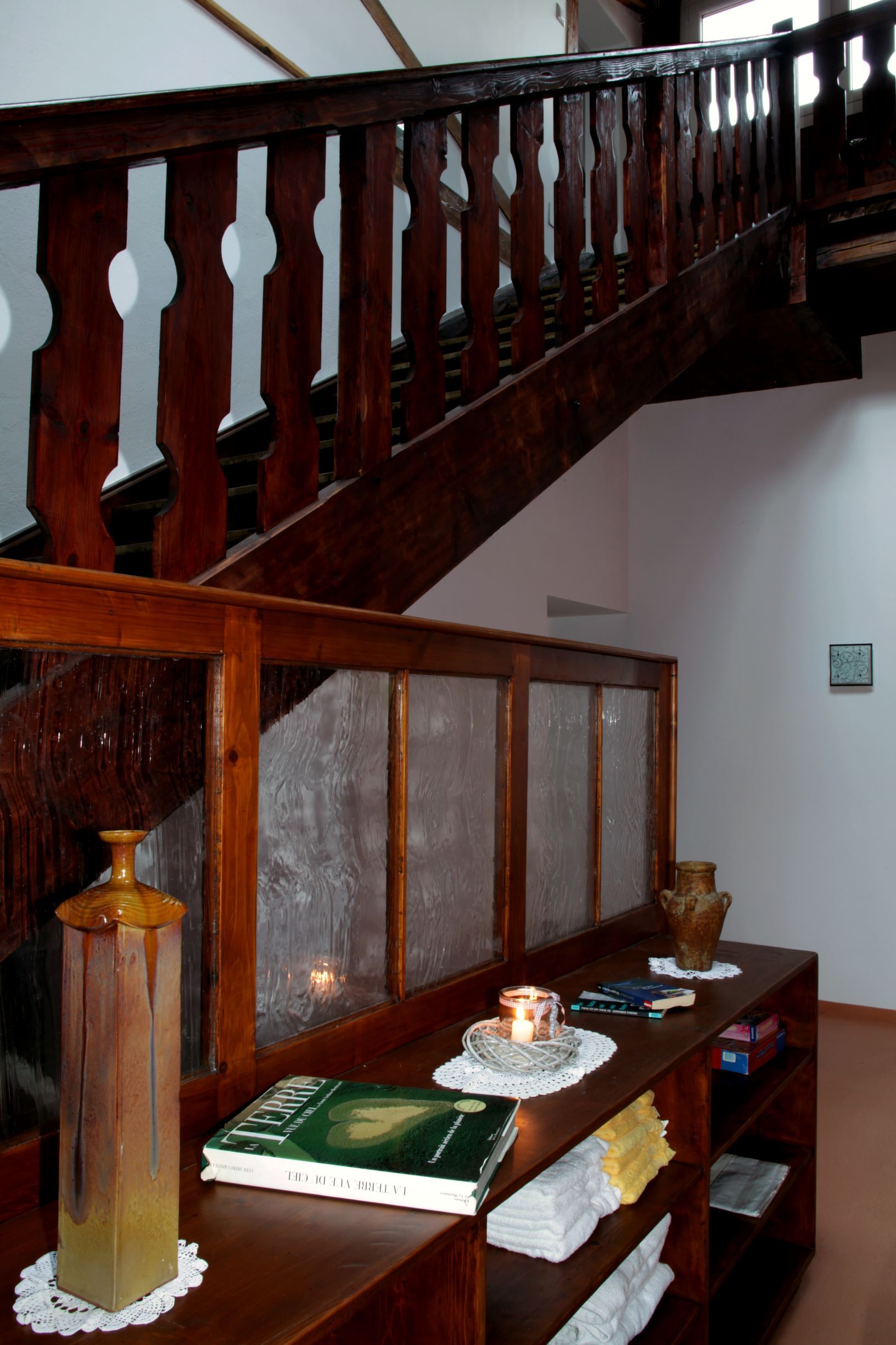 Wooden staircase in a loft with decorative elements and books on a shelf.