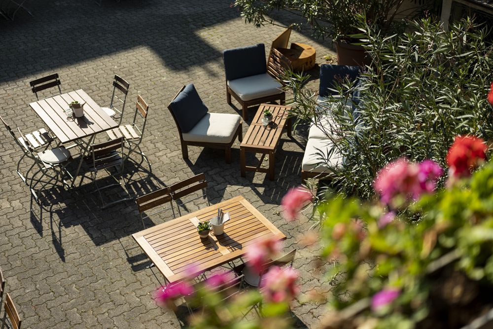 Cozy outdoor area with wooden furniture and plants, sunny atmosphere.