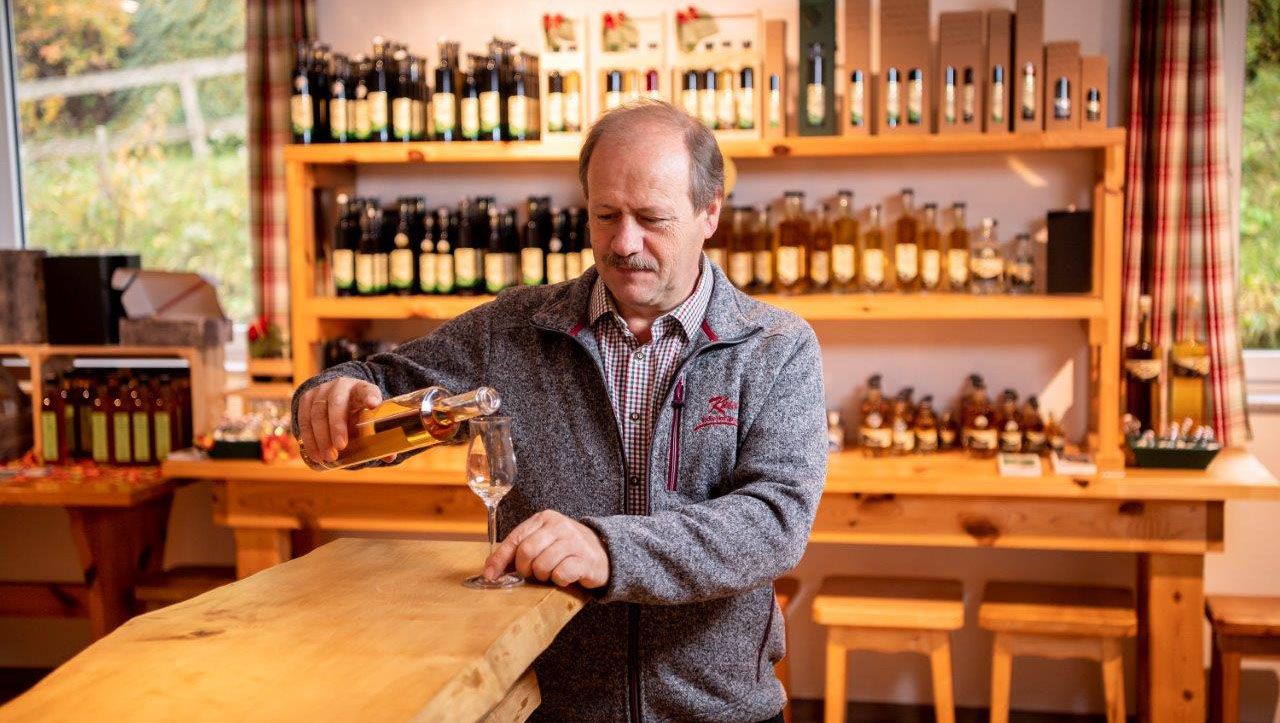 A man pours schnapps into a glass in a tasting room.