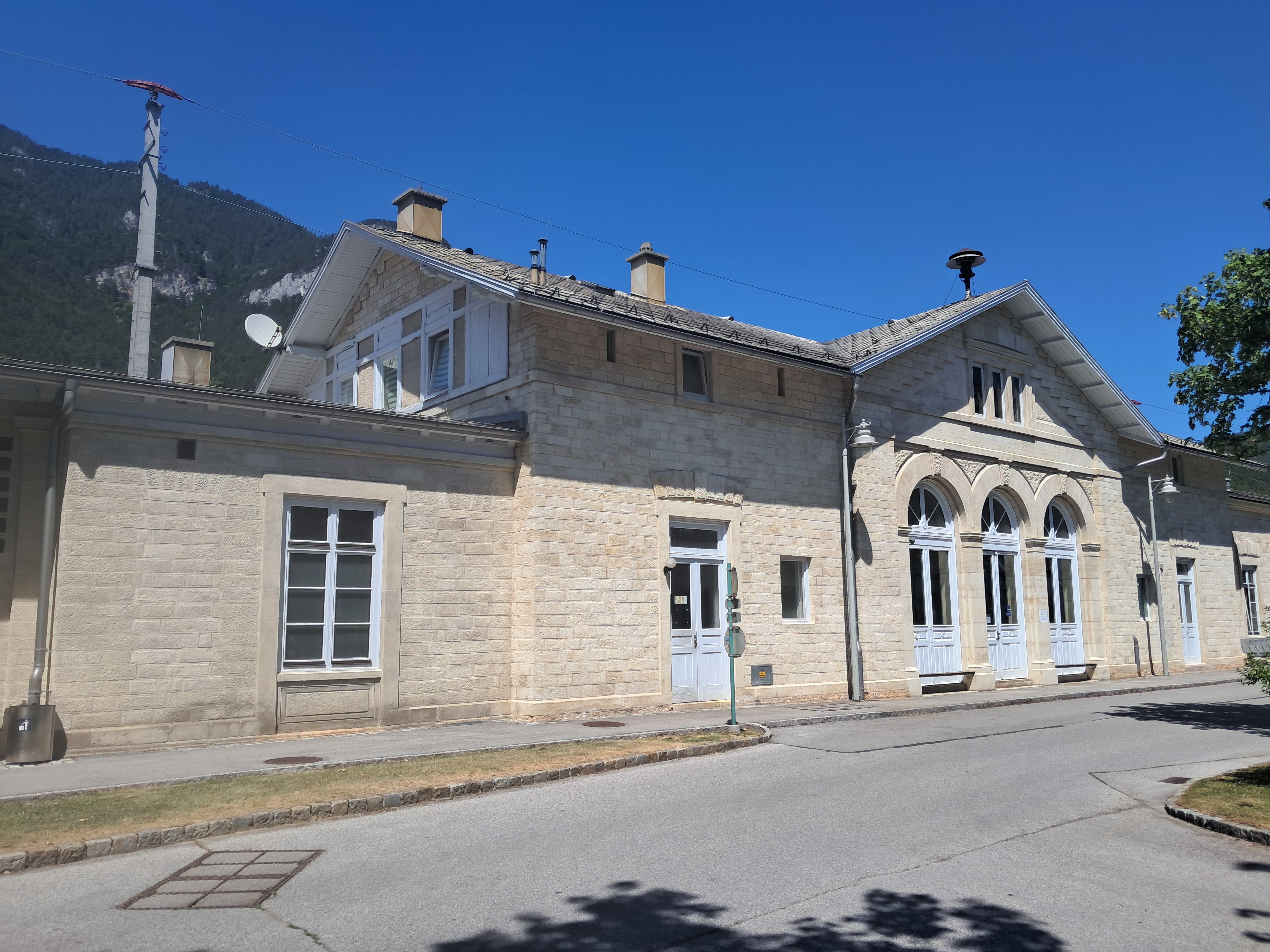 Payerbach-Reichenau station with historic building and blue sky.