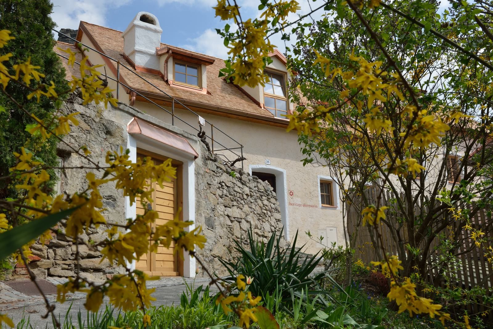 Stone house with yellow flowers in the foreground in Dürnstein.