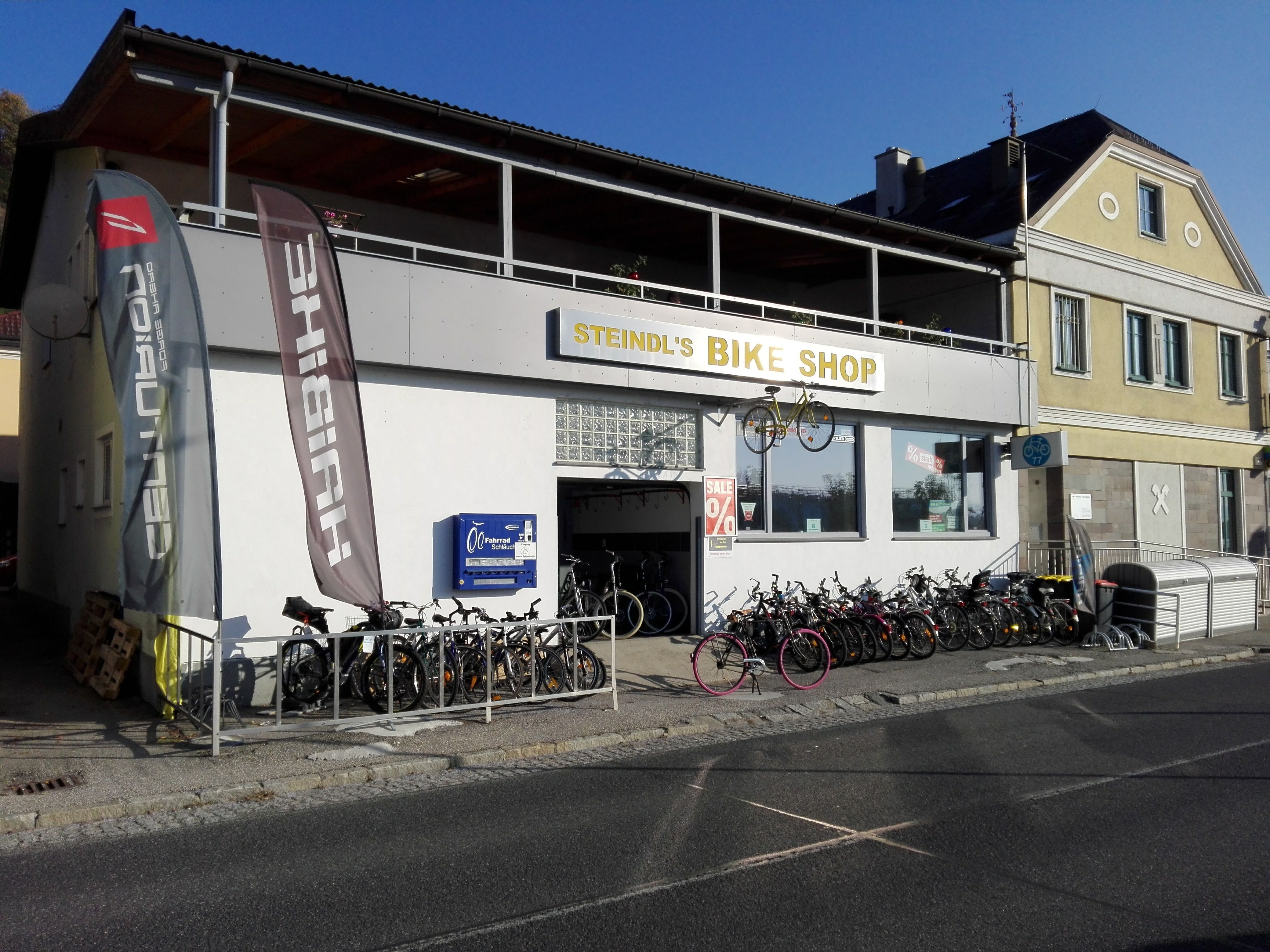 Bicycle store with bicycles in front of the building and advertising flags.