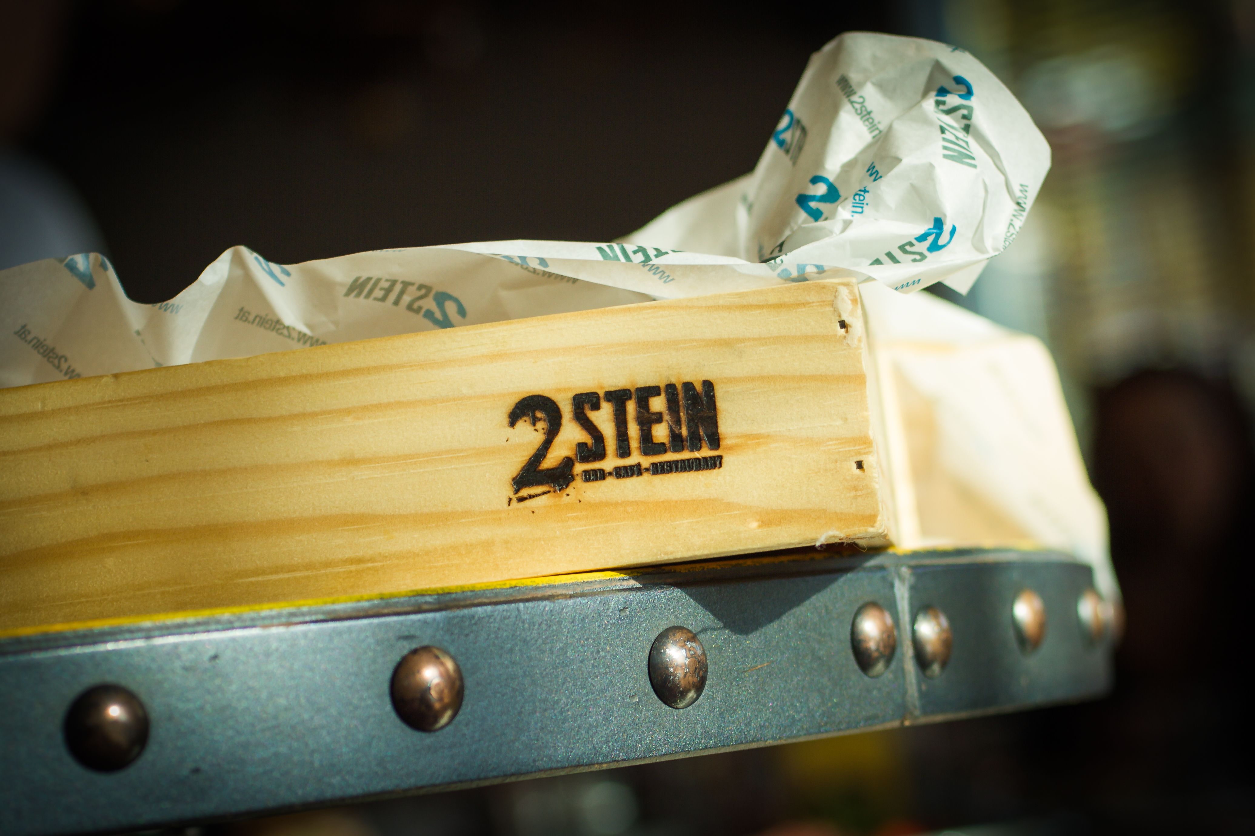 Wooden box with 2Stein logo and paper in the background.